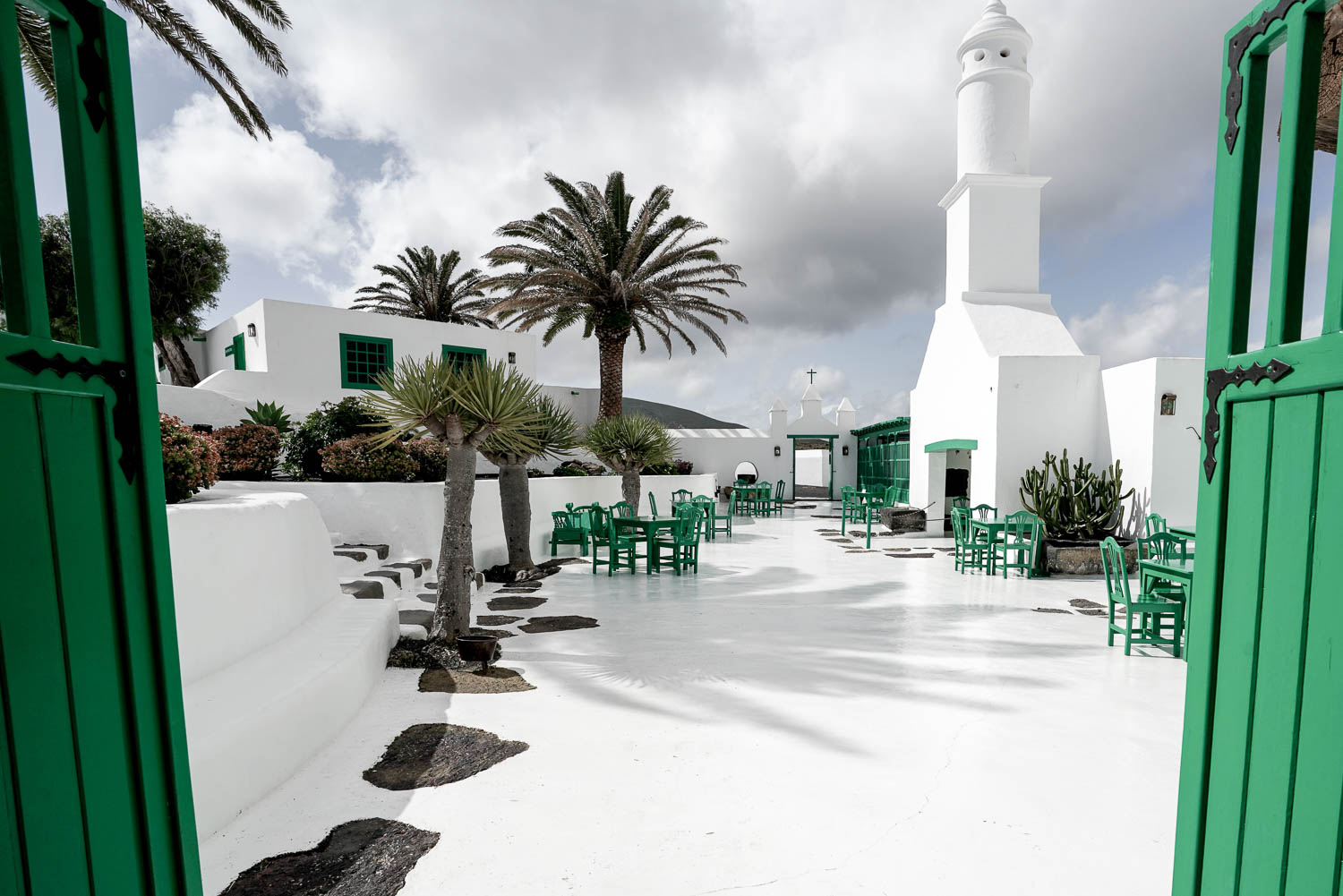 Tradiční bílý dvorek na Lanzarote se zelenými dveřmi a zelenými židlemi – typická místní architektura
