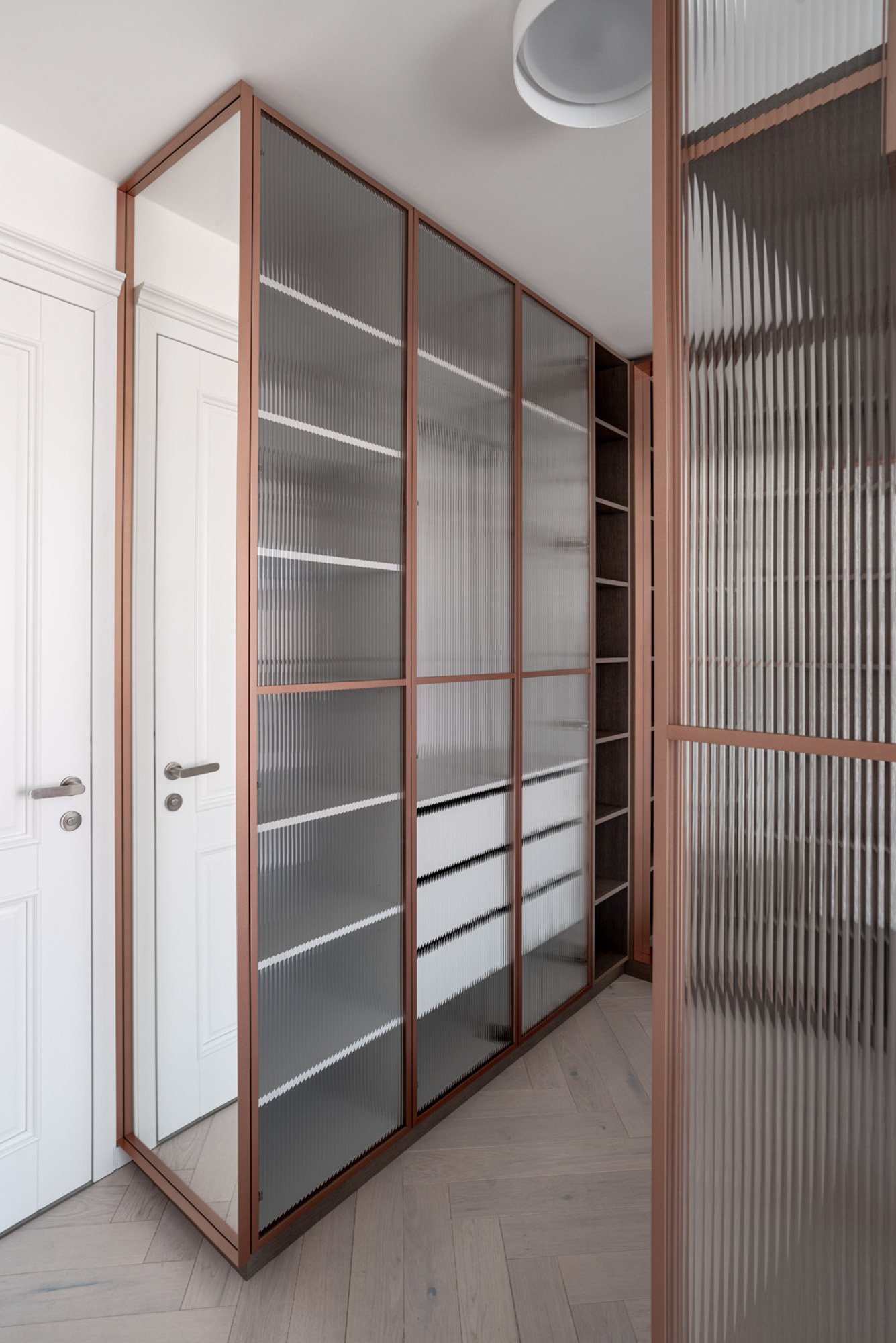 Detail crittall příčky z měděného profilu s rýhovaným dekorativním sklem — precizní ručně lakovaný rám a optika ribbed skla