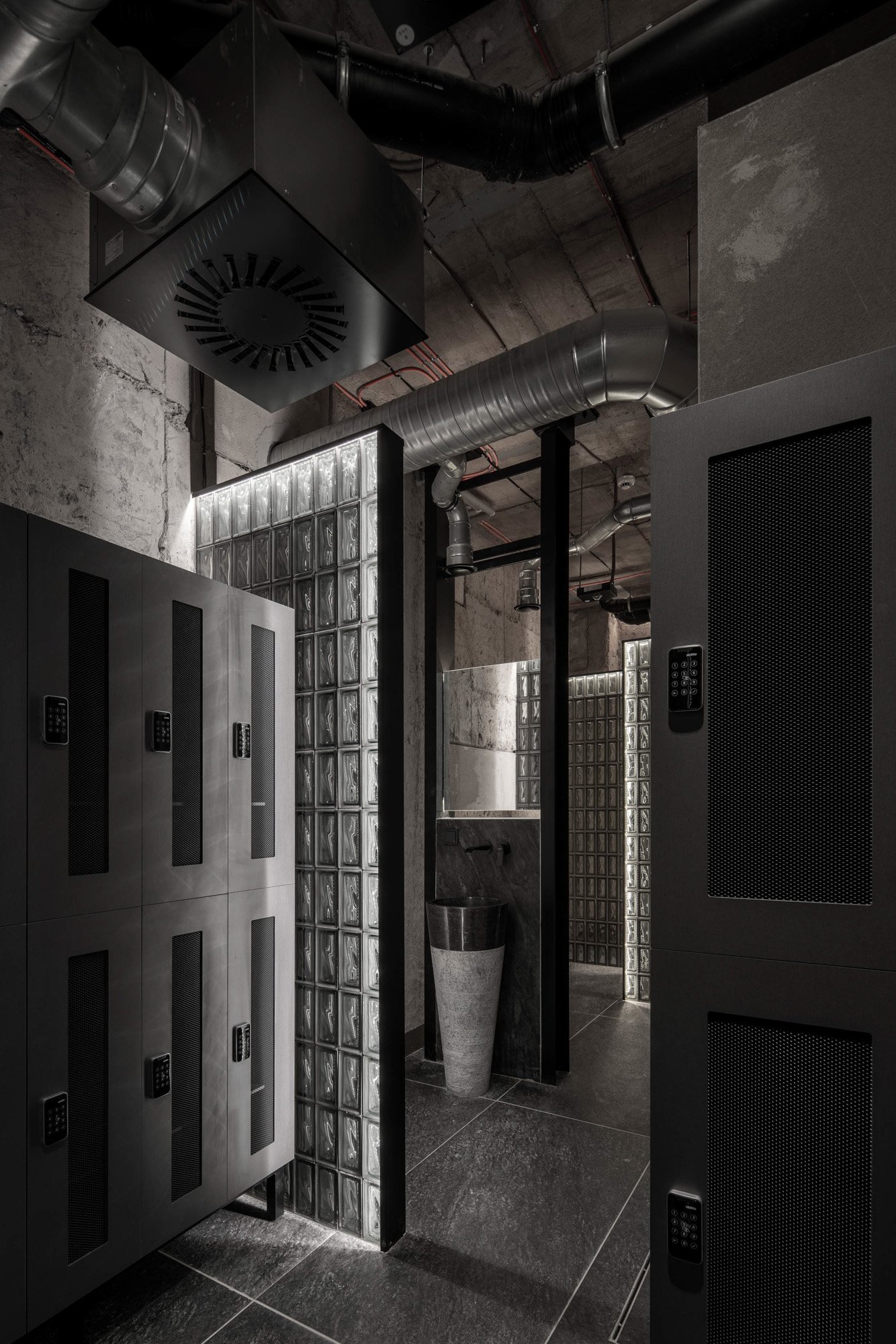 Industriální prostor s příčkou ze skleněných luxfer a crittall příčkou — pohled z druhé strany prostoru