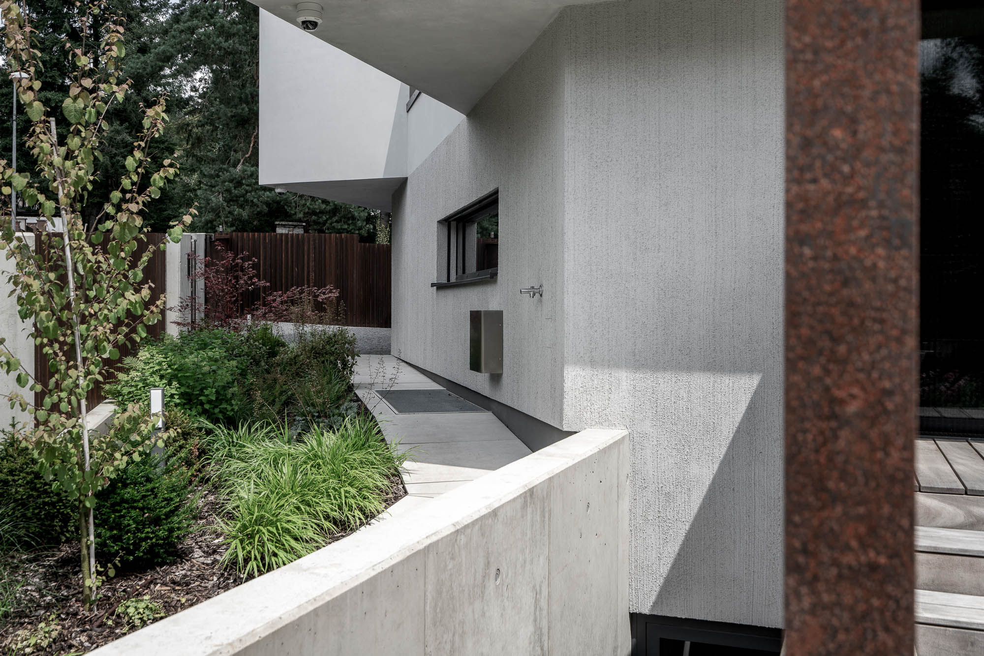 Villa Lučiny exterior — textured STO plaster facade and corten garden elements OOOOX Prague