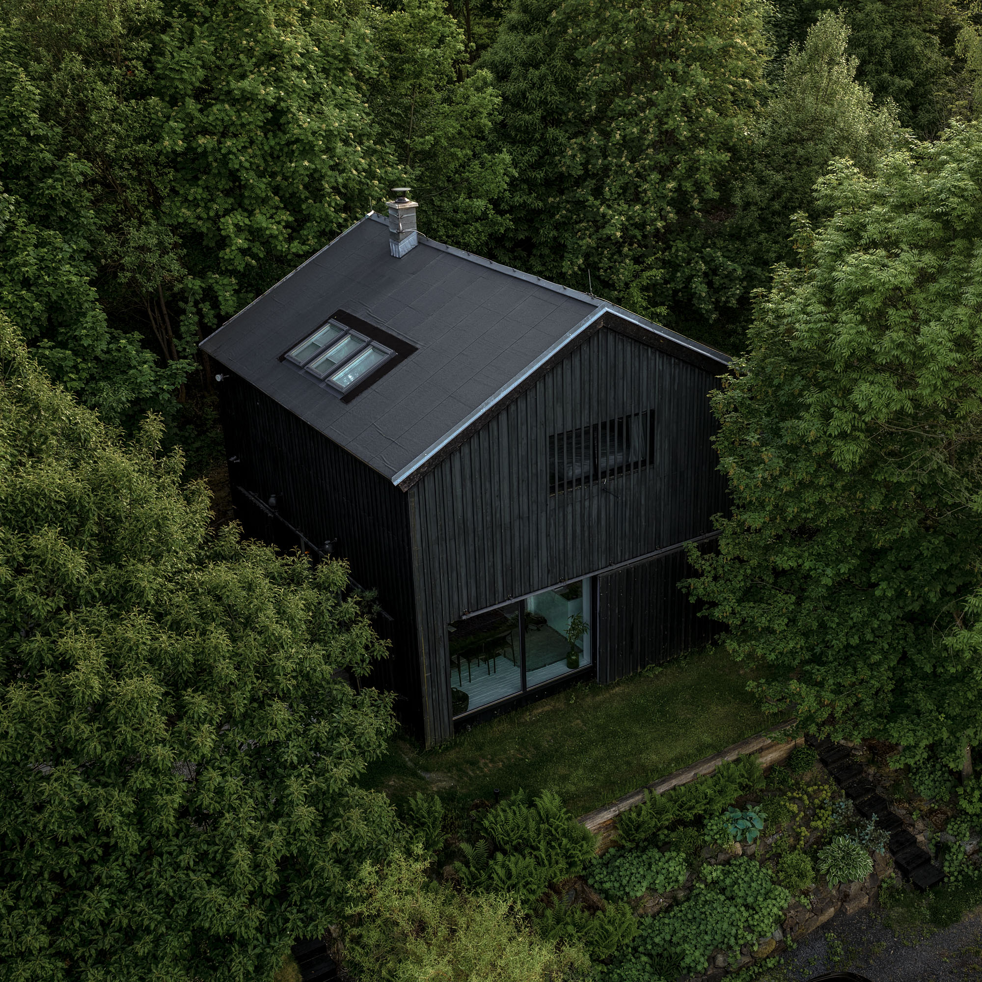 BOX barn conversion — black vertical timber cladding, large panoramic window, garden slope with stacked logs, pool on the slope | OOOOX