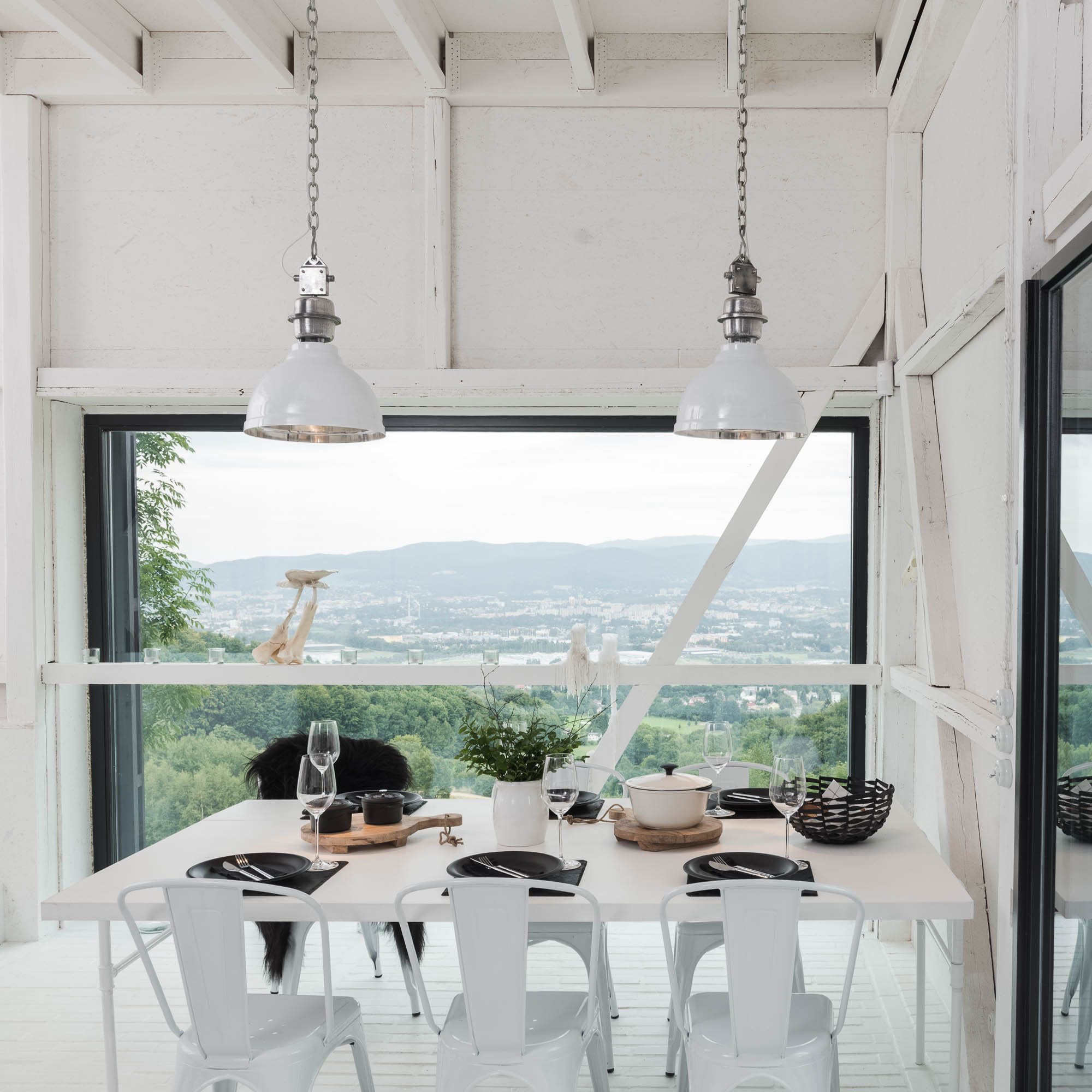 BOX barn conversion white interior — dining table with white metal Tolix chairs, industrial pendant lights, large window with countryside view | OOOOX
