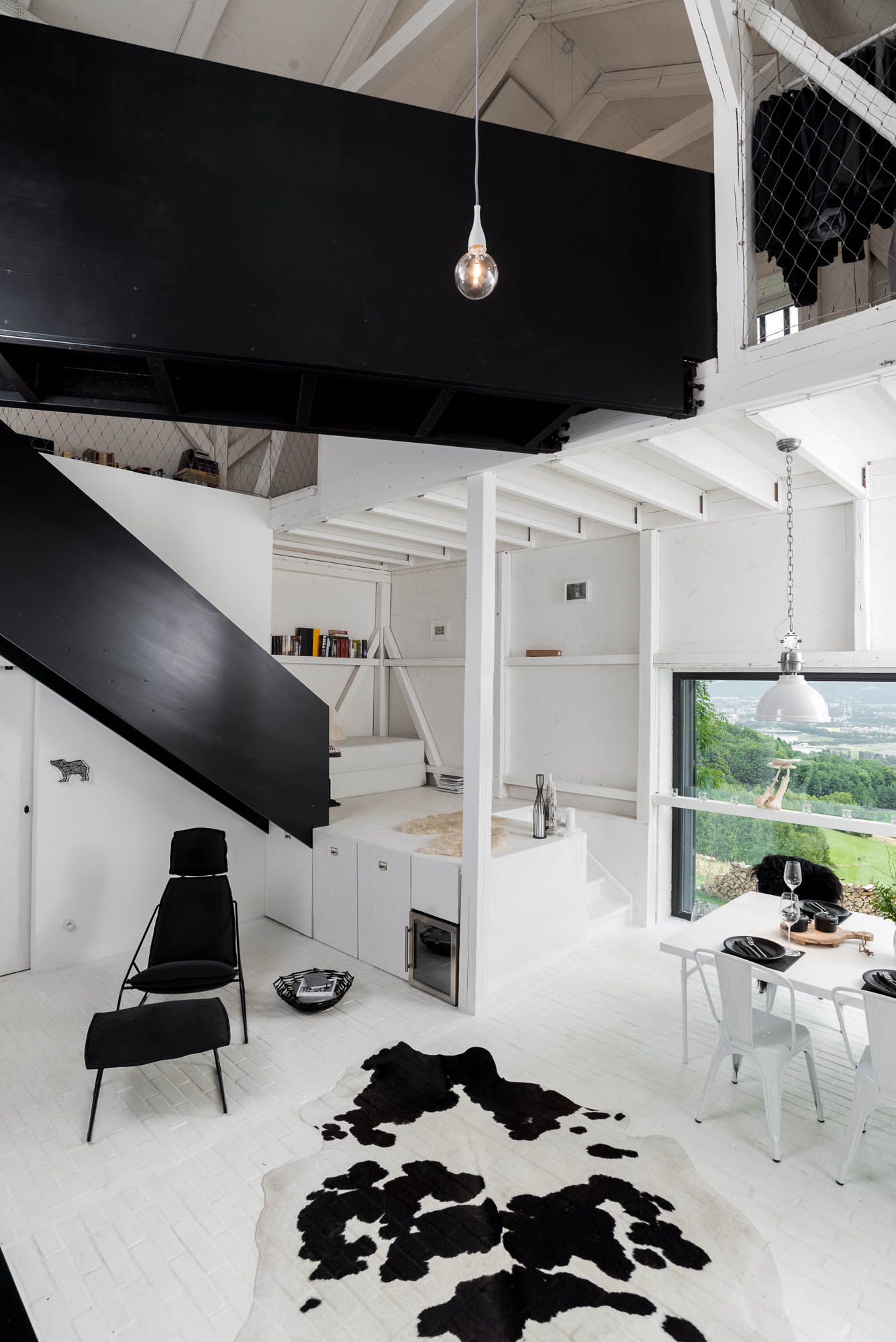 BOX barn conversion full interior overview — black steel staircase, living area with cowhide rug, reading podium, double-height vaulted ceiling | OOOOX