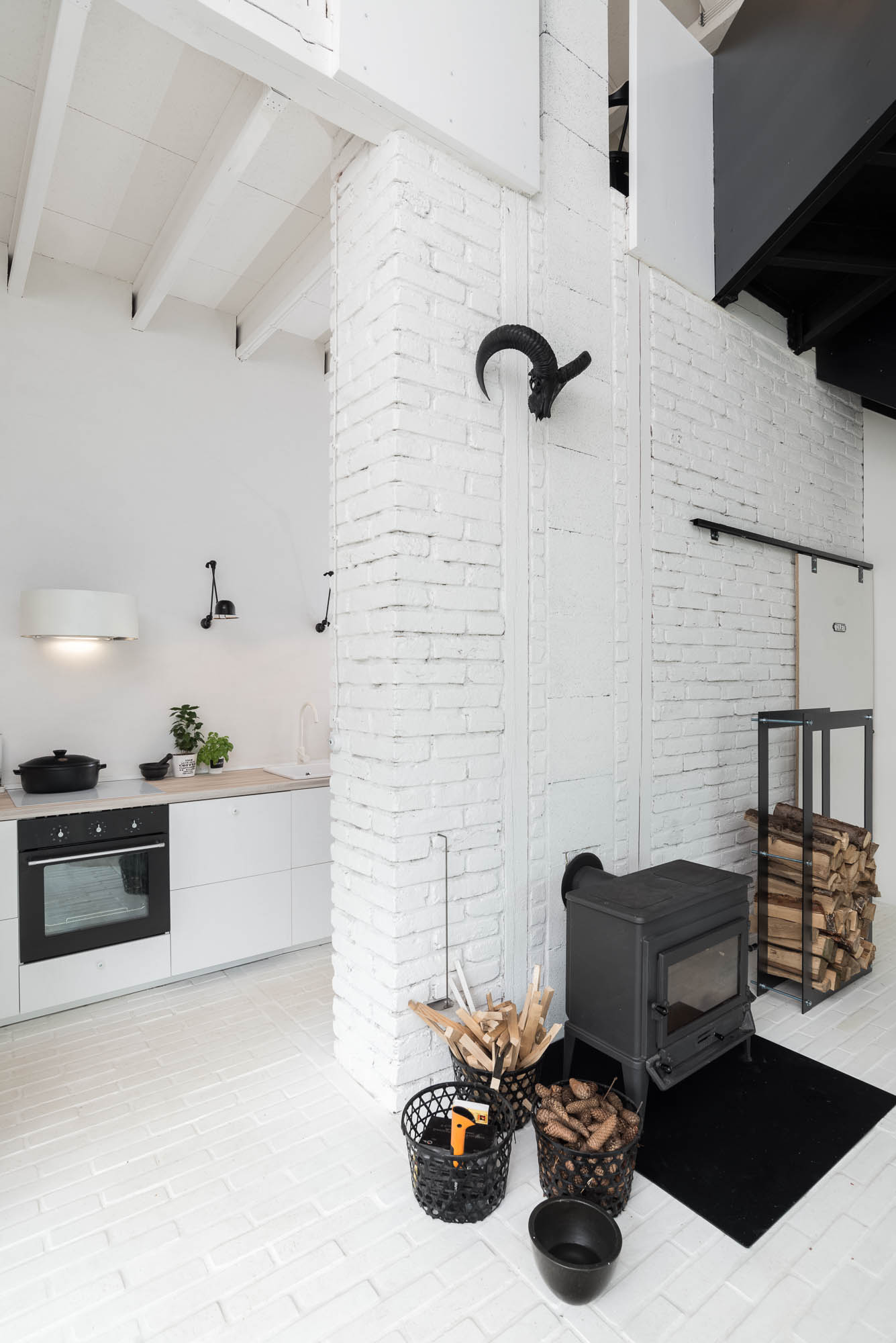 BOX barn kitchen zone — white kitchen units adjacent to white painted brick partition, ram skull wall decoration, stove visible in background | OOOOX