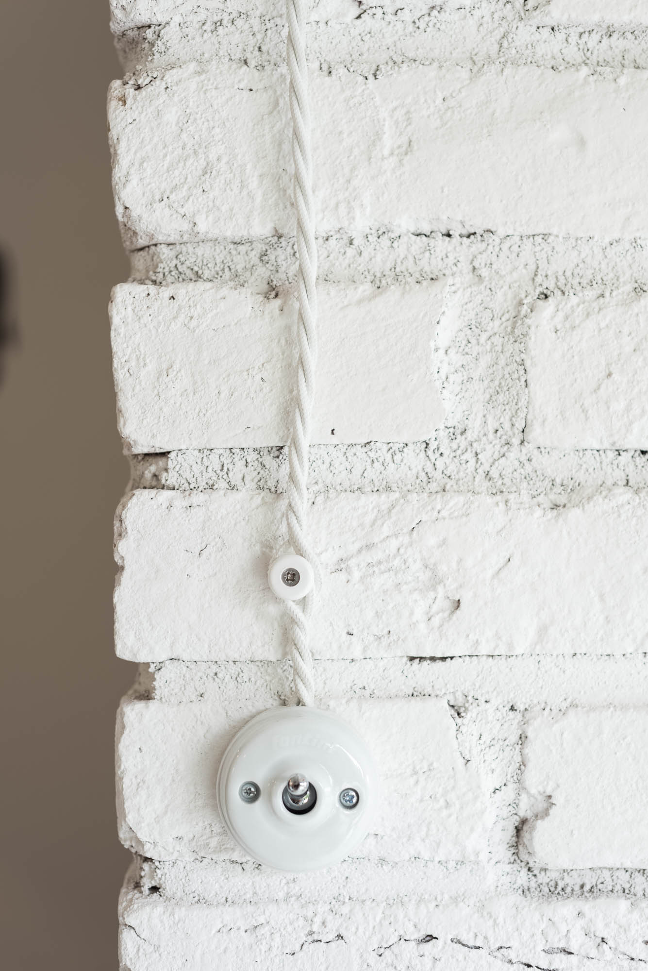 BOX barn detail — retro white porcelain toggle light switch with twisted fabric cable on white painted brick wall | OOOOX