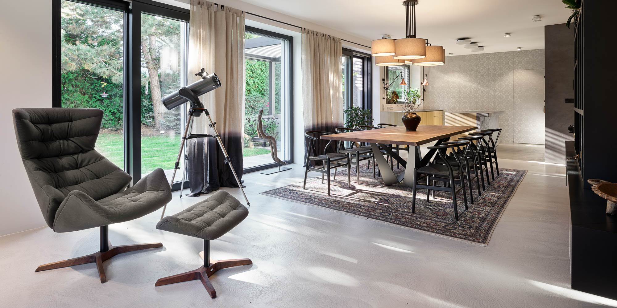 Open-plan living dining view from kitchen grey armchair copper wall sconce garden villa OOOOX