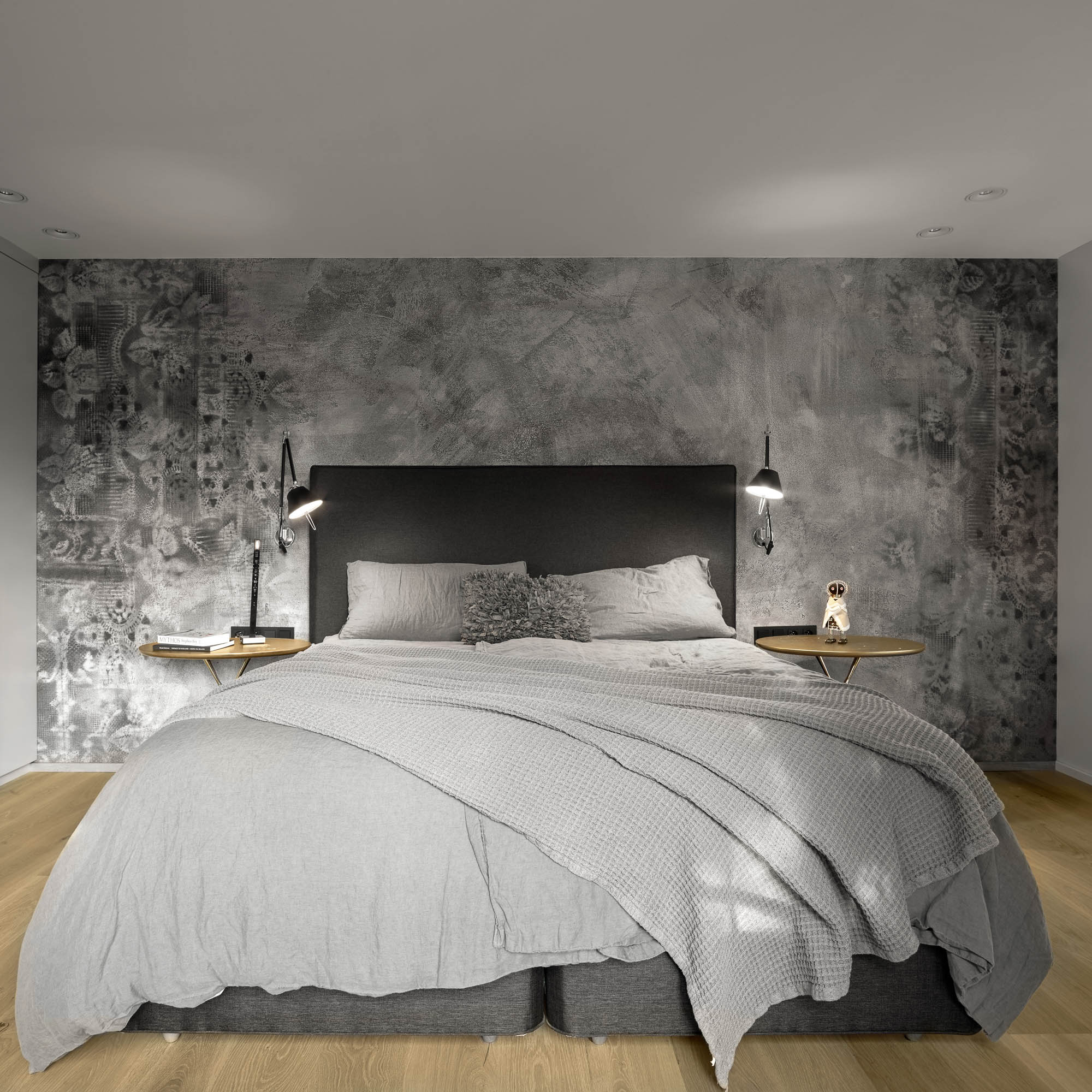 Symetrický pohled na antracitovou postel, vzorovanou tapetu Wall and Deco a zlaté noční stolky Cassina | OOOOX