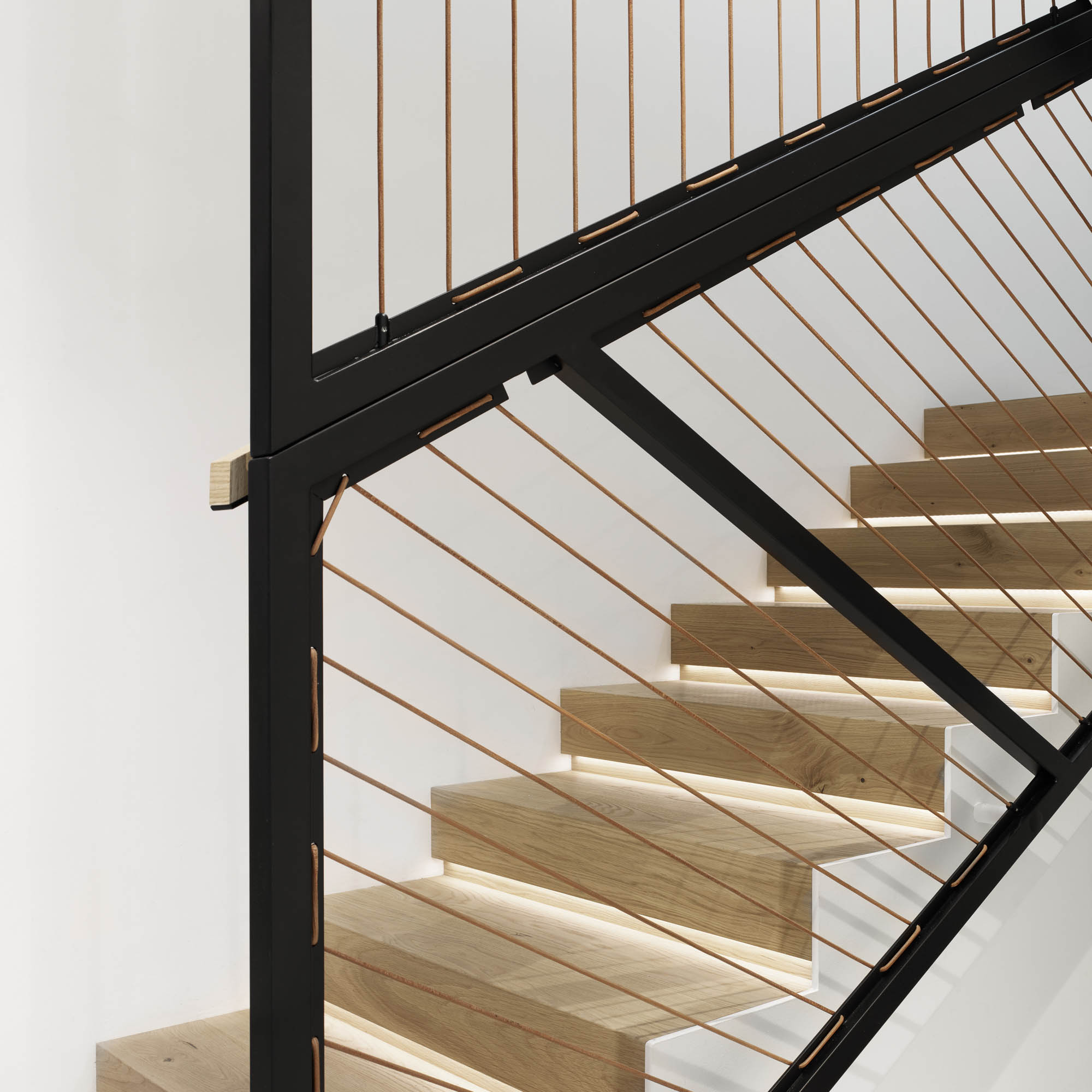 Staircase close-up different angle black steel balustrade leather cord weave LED backlit oak steps OOOOX