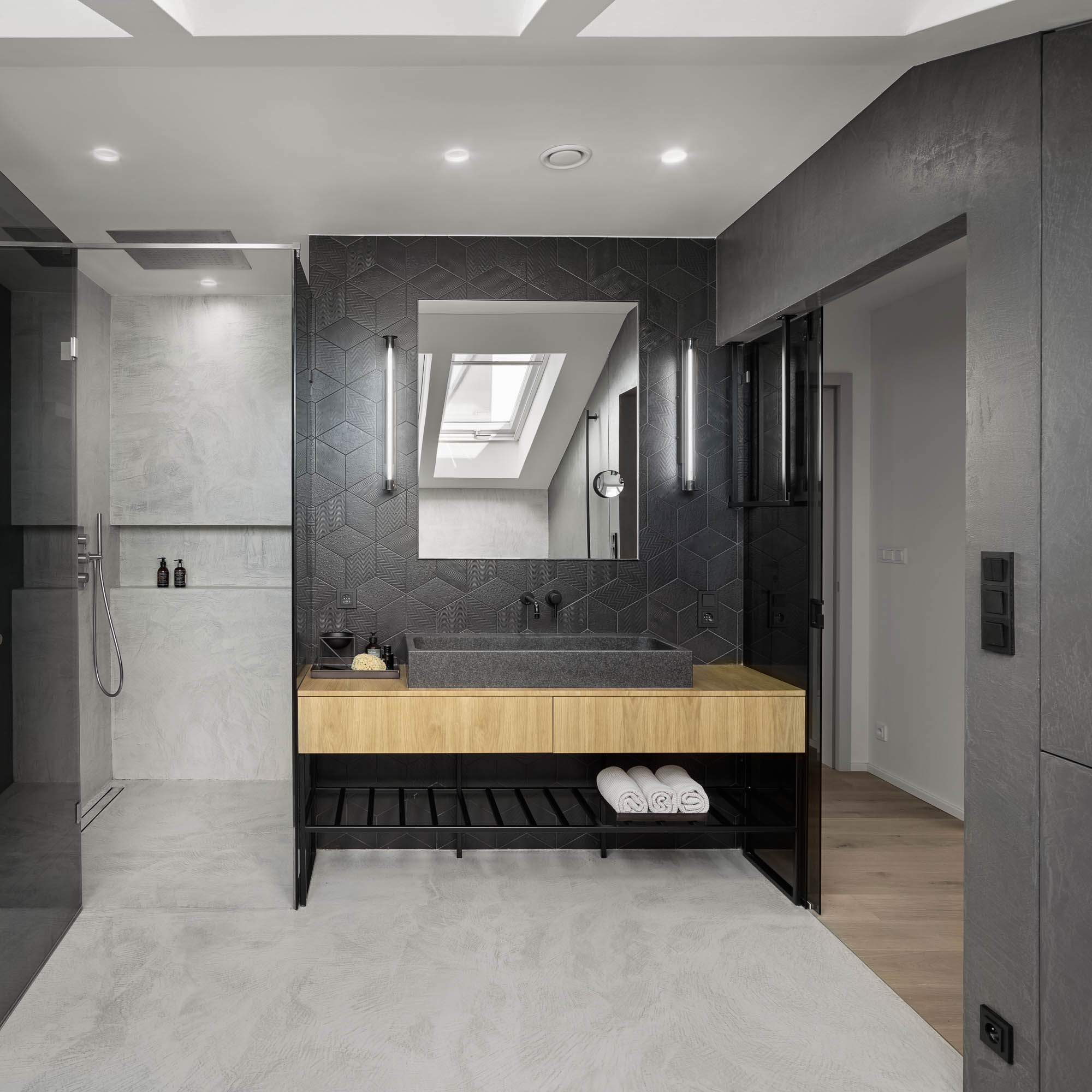 Master bathroom dark geometric ceramic tile stone vessel sink oak floating vanity skylight LED sconces OOOOX