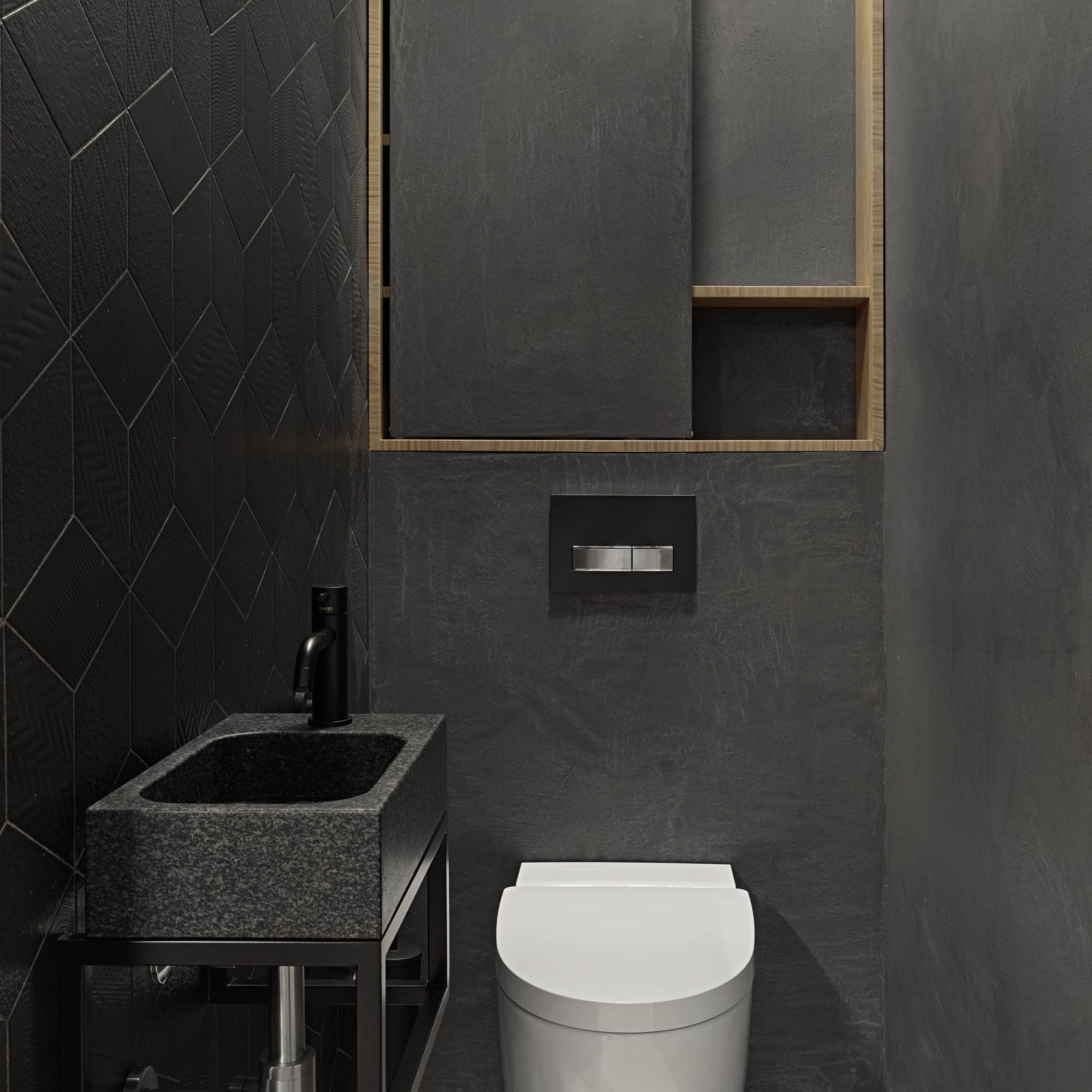 Tmavé WC s černým geometrickým obkladem, kamenným umyvadlem, závěsným WC a dubovým zrcadlovým výklenkem | OOOOX