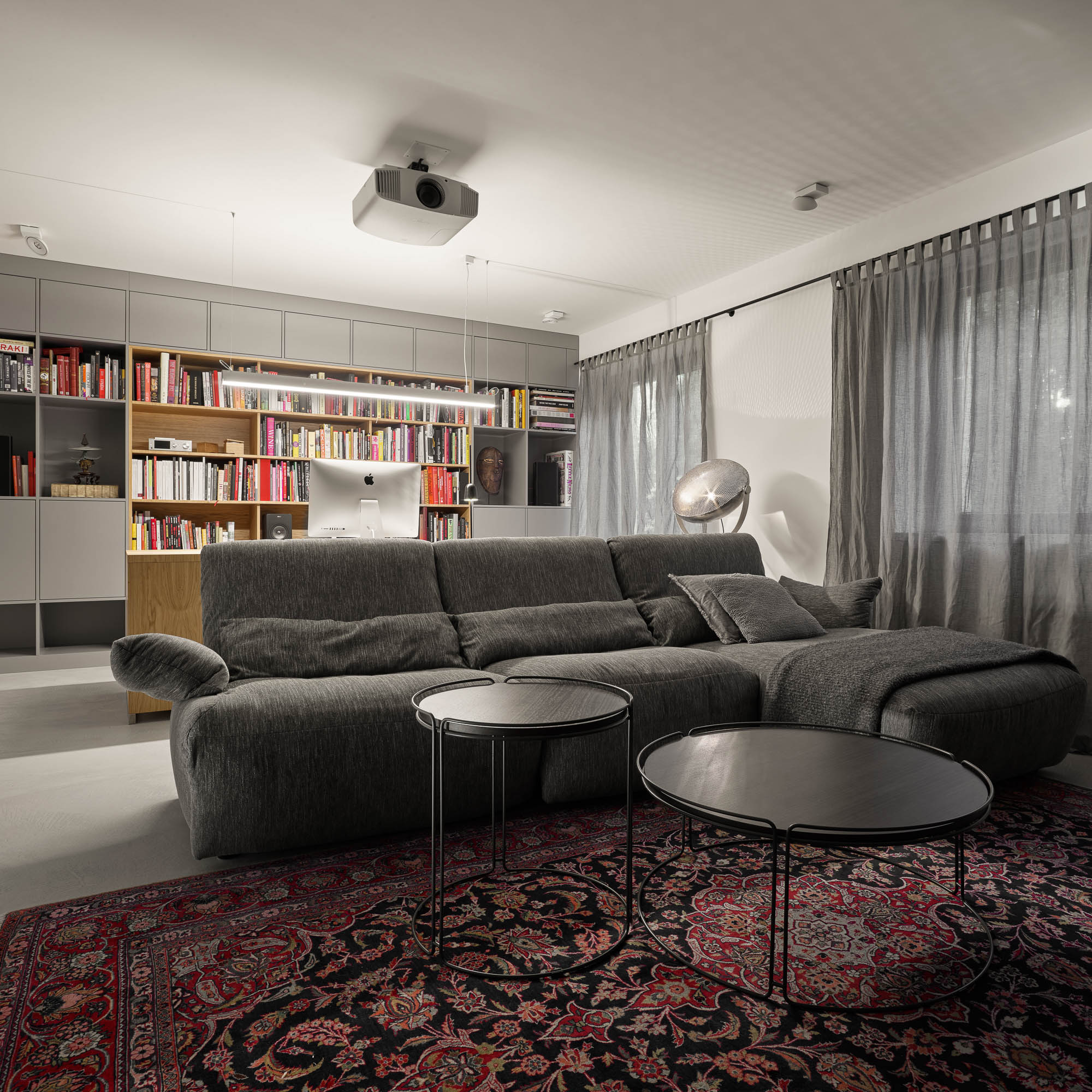 Home office study room grey sectional sofa projector system MDF bookshelf oak section iMac Persian rug OOOOX