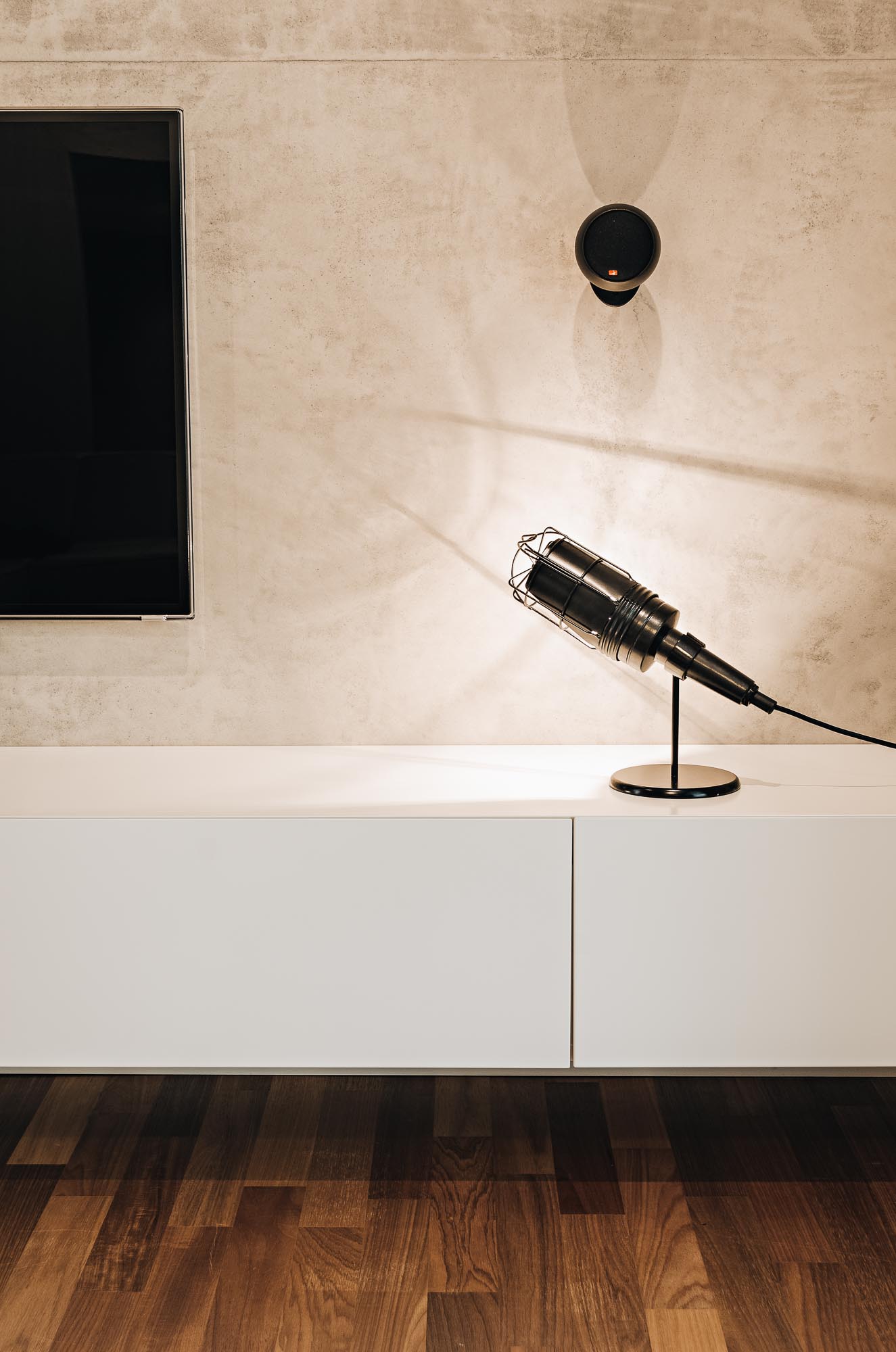 Detail industriální klecové lampičky na bílém TV dílu s betonovou stěrkou | OOOOX
