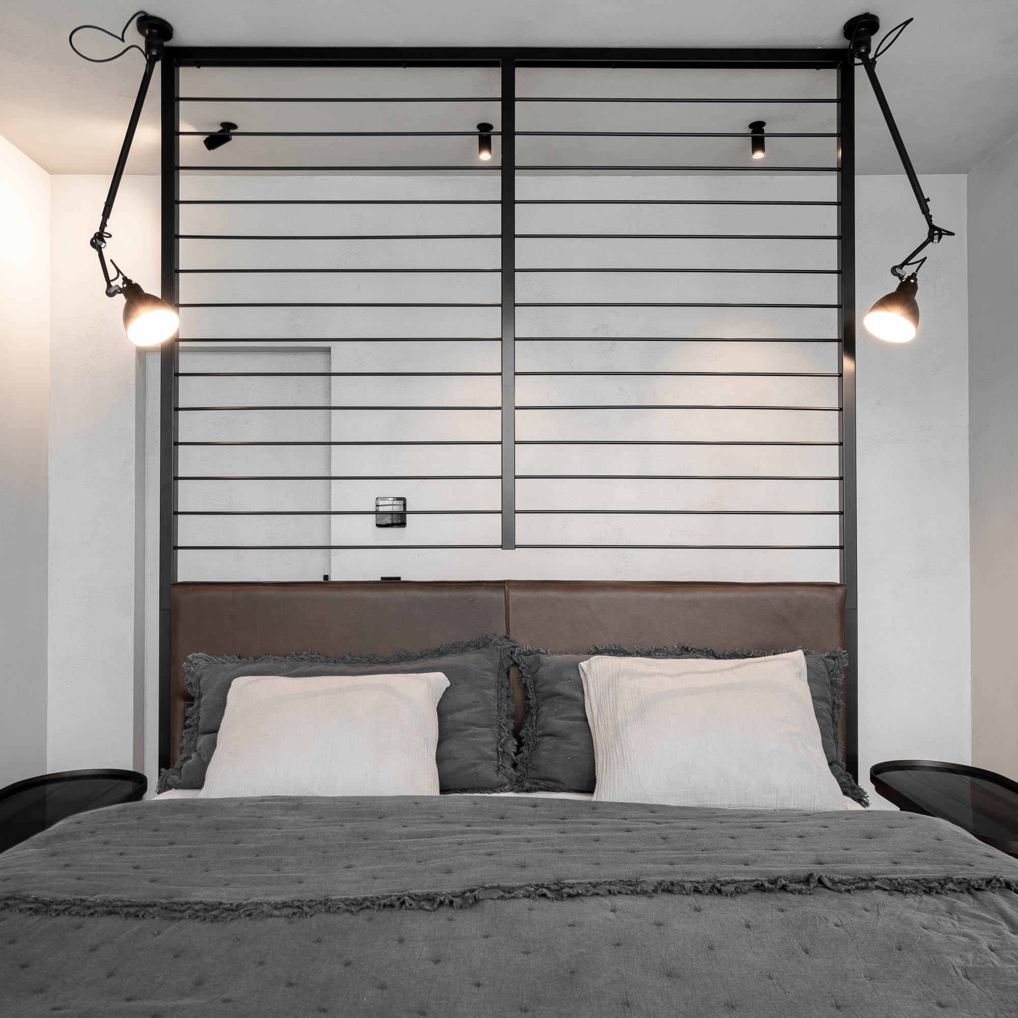 Ložnice v mezonetu s postelí v prostoru a ocelovou konstrukcí za čelem