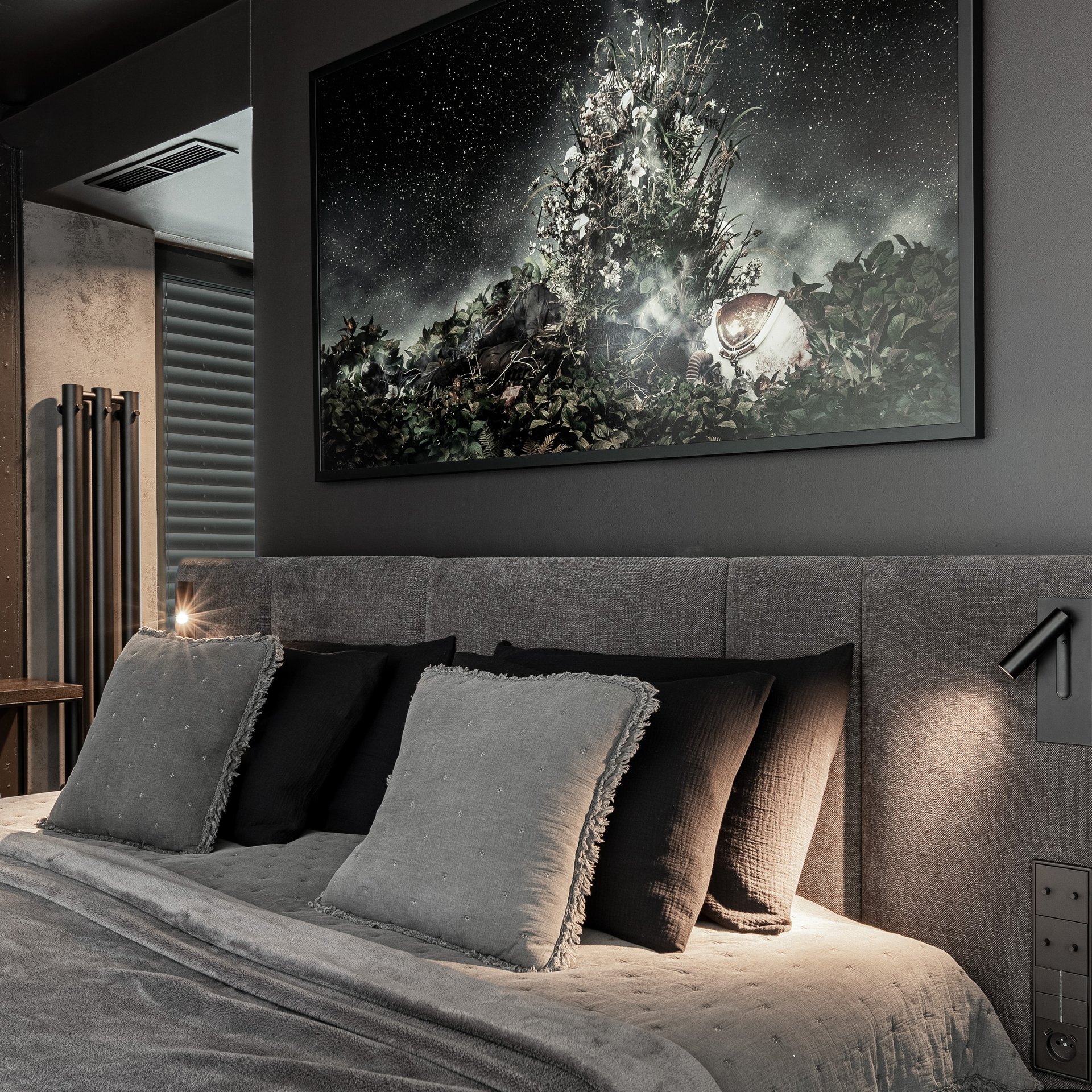 Detail čela postele ložnice vily Hřebenky – šedé čalounění s integrovanými čtecími lampičkami, tmavý umělecký fotografický tisk (kytky ve vesmíru), šedé a tmavé dekorační polštáře s třásněmi