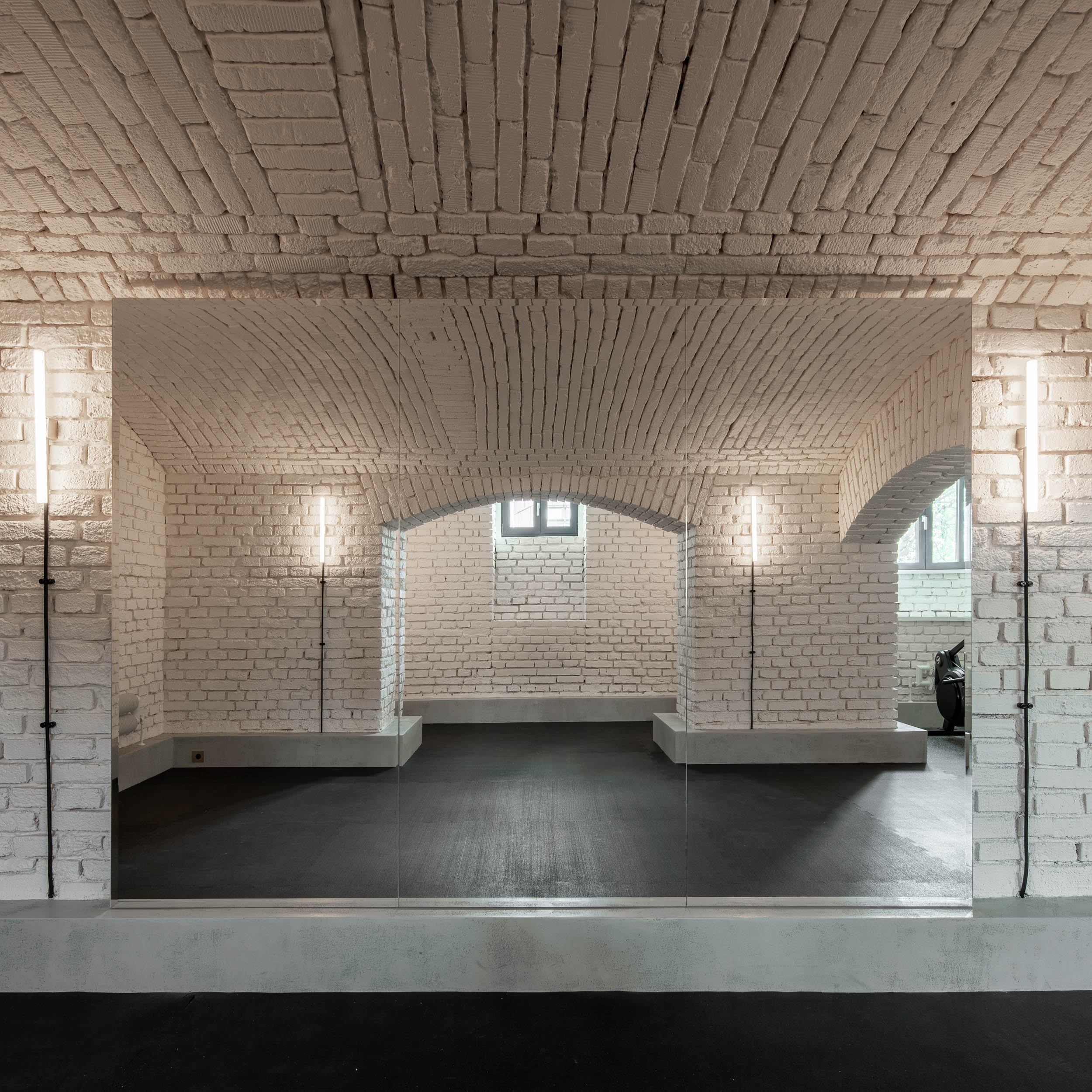 Gym in the basement of Villa Vinohrady with exposed brick walls and vaulted ceilings – minimalist interior and reconstruction by OOOOX