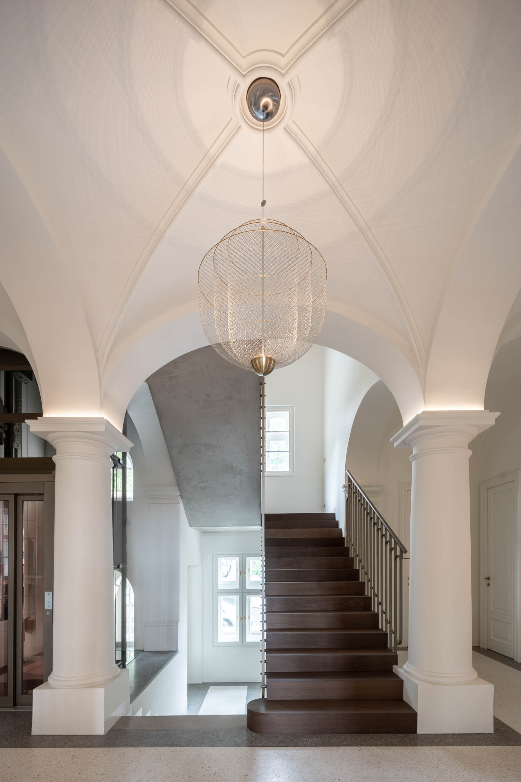 Entrance hall of Villa Vinohrady with new terrazzo flooring featuring an inset brass frame and delicate railing of the concrete staircase | reconstruction design by OOOOX