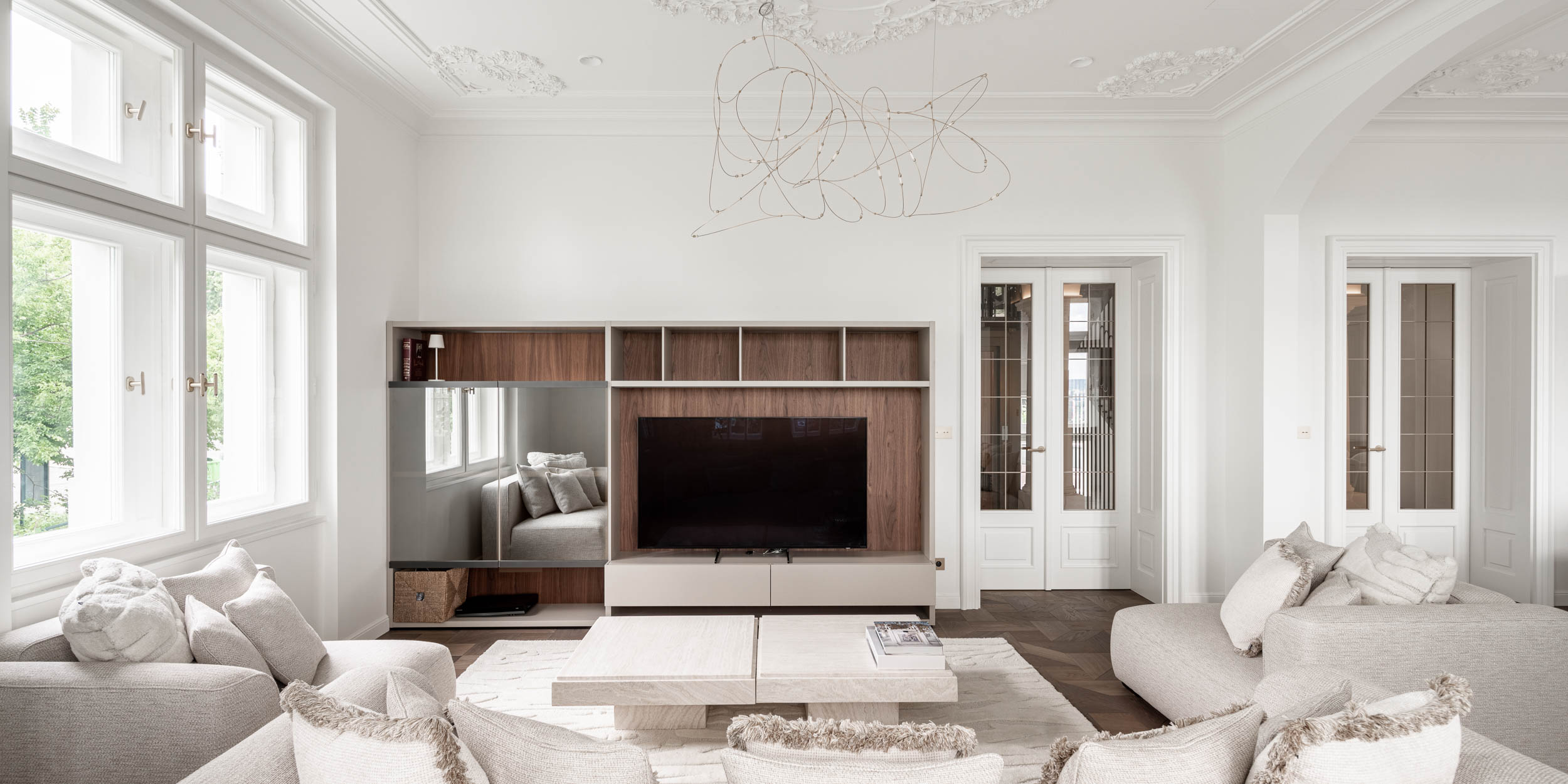 Living room with a built-in TV cabinet, white walls, stucco ceilings and a delicate wire designer light fixture enhancing the airiness of the space | reconstruction design by OOOOX