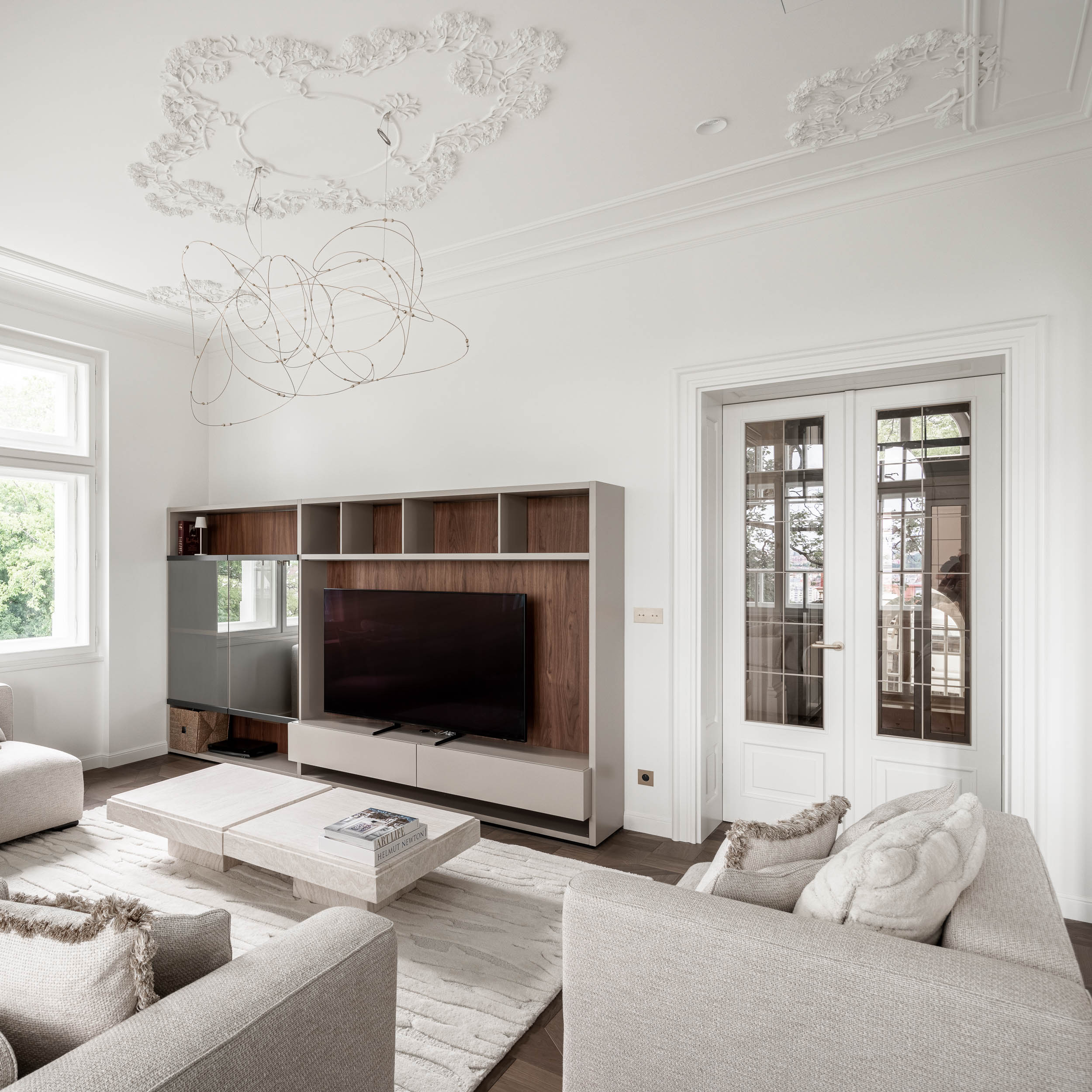 Living room with a built-in TV cabinet, white walls, stucco ceilings and a delicate wire designer light fixture enhancing the airiness of the space | reconstruction design by OOOOX