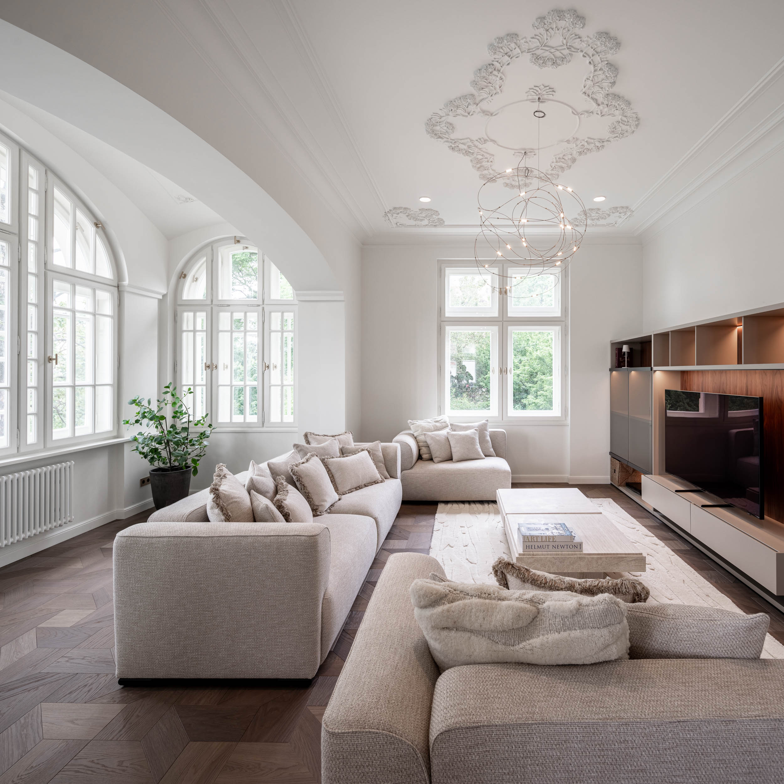 Living room with a built-in TV cabinet, white walls, stucco ceilings and a delicate wire designer light fixture enhancing the airiness of the space | reconstruction design by OOOOX