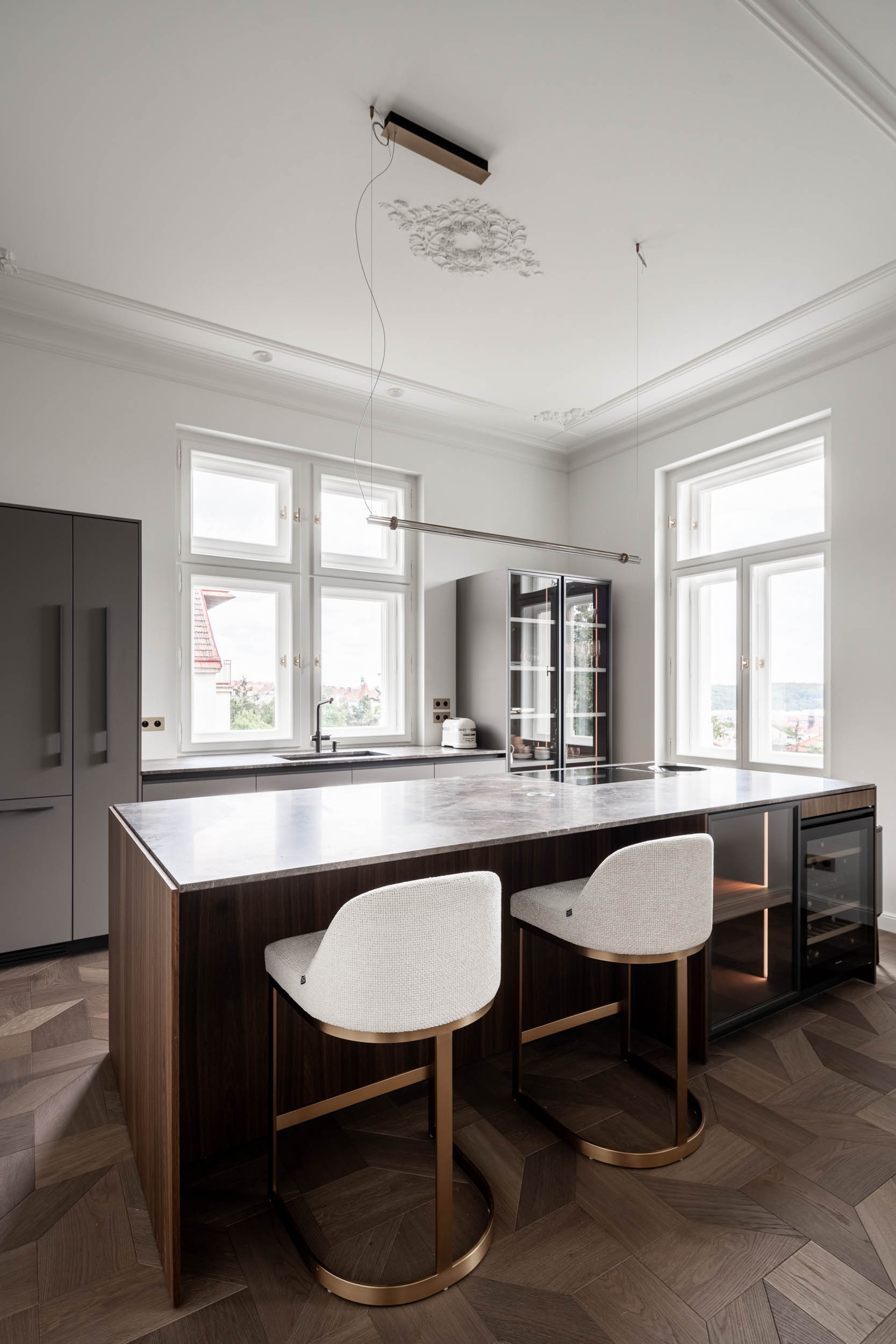 Serving kitchen with a brass bar island, stucco ceilings and daylight illumination in the interior of Villa Vinohrady by OOOOX