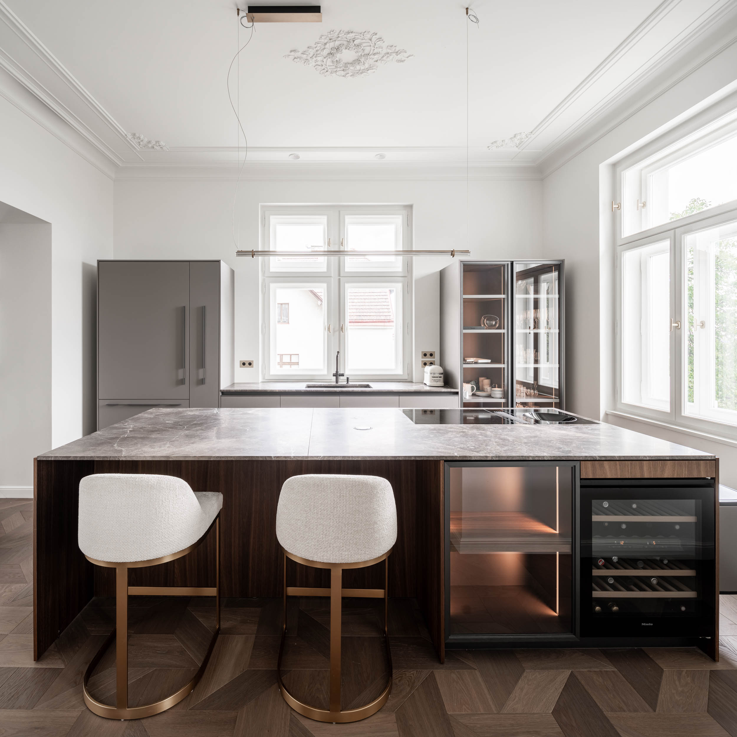 Serving kitchen with a brass bar island, stucco ceilings and daylight illumination in the interior of Villa Vinohrady by OOOOX