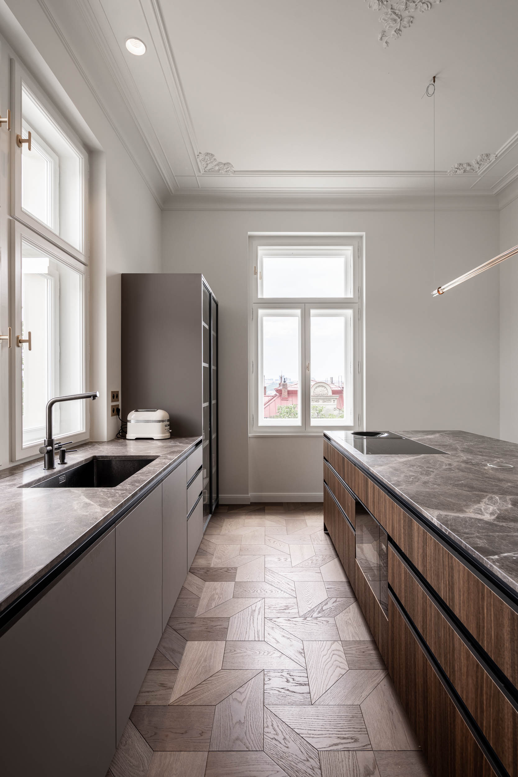 Serving kitchen with a brass bar island, stucco ceilings and daylight illumination in the interior of Villa Vinohrady by OOOOX