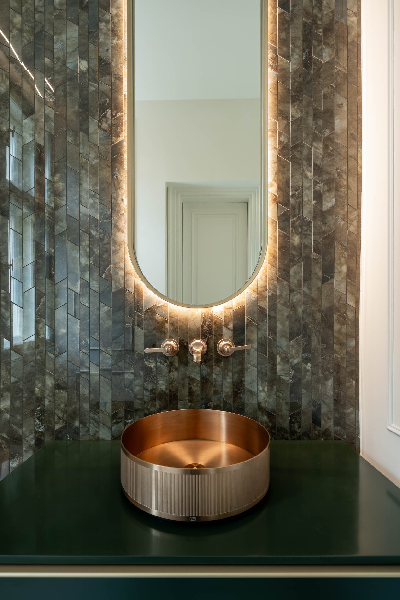Bathroom clad in green marble stone mosaic with a brass sink and faucets inspired by the 1930s | Villa Vinohrady reconstruction design by OOOOX