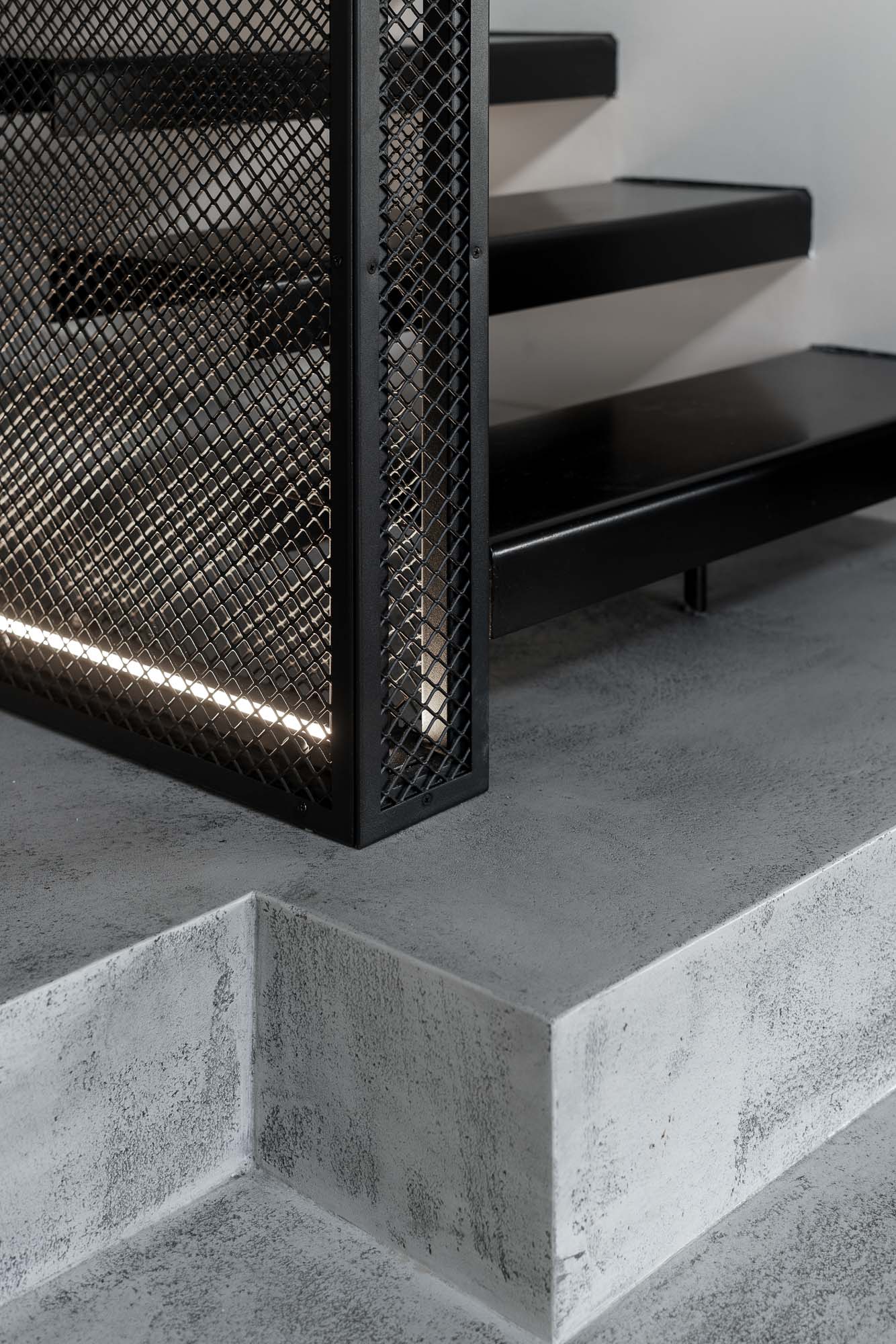 Detail of a steel staircase with expanded metal railing and floating structure in an industrial loft interior. Design by OOOOX