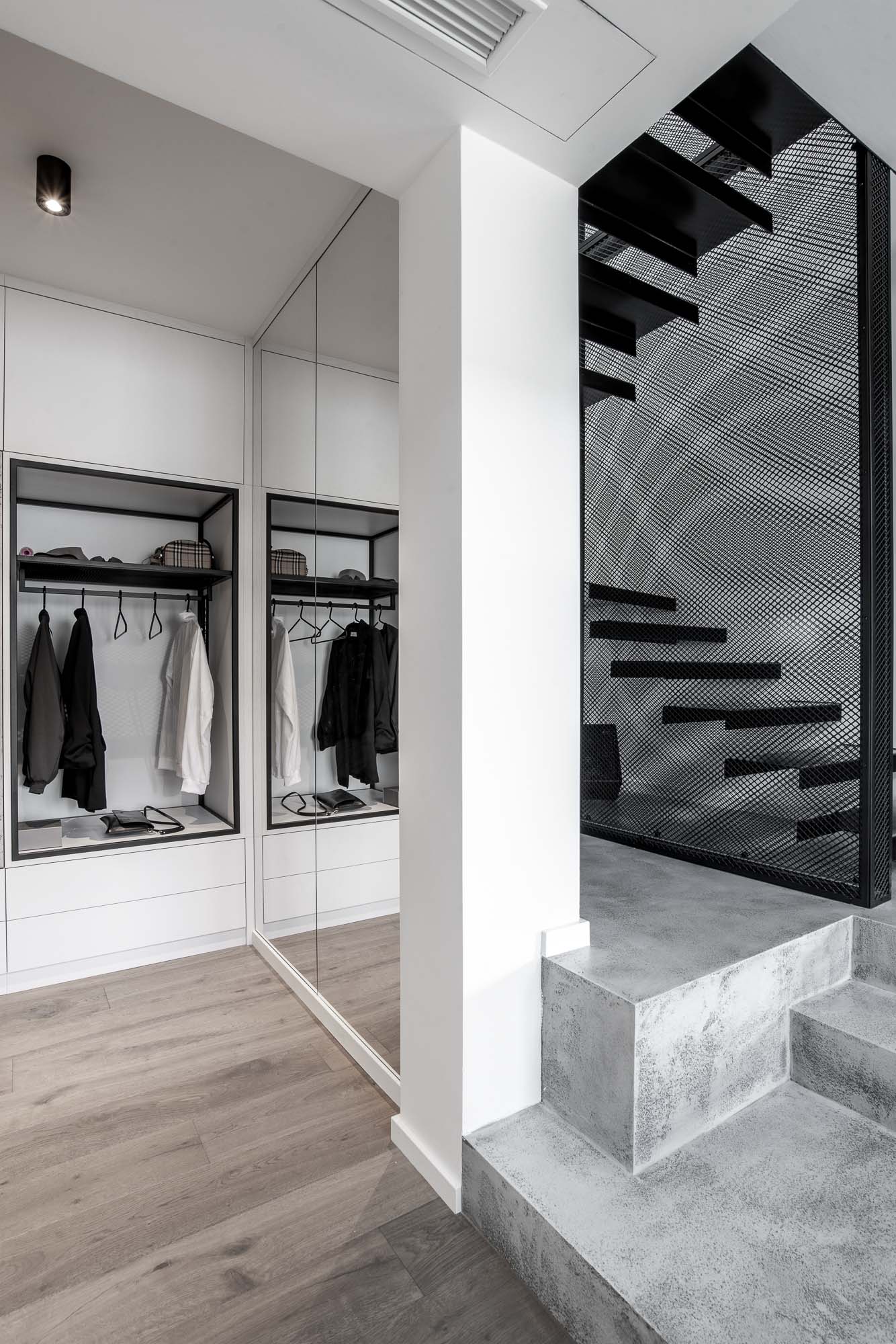 Pohled do šatny s vestavěnými úložnými prostory, dubovou podlahou a minimalistickým industriálním řešením interiéru. Design by OOOOX