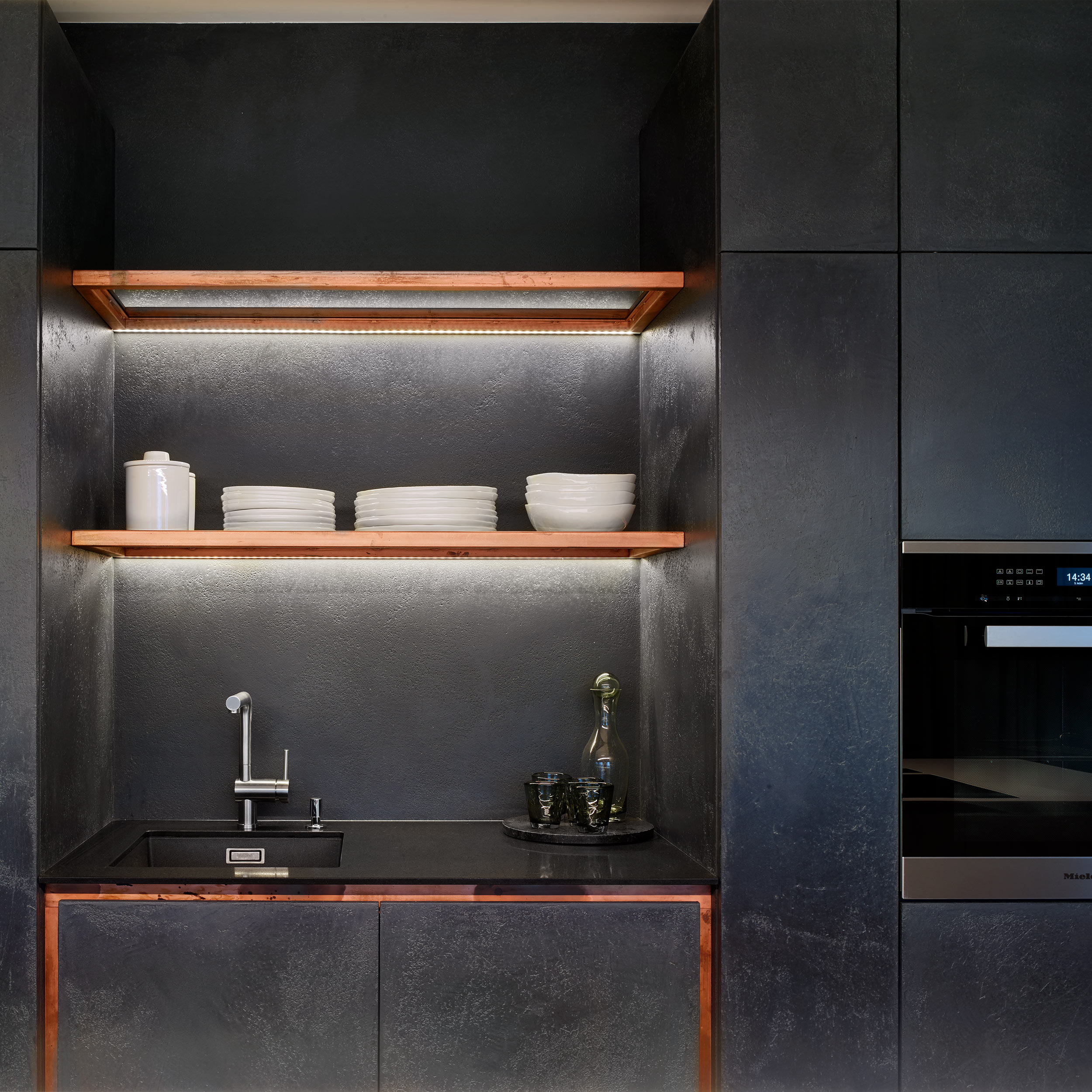 Detail černé kuchyňské linky s měděnými akcenty – minimalistický interiér novostavby | OOOOX