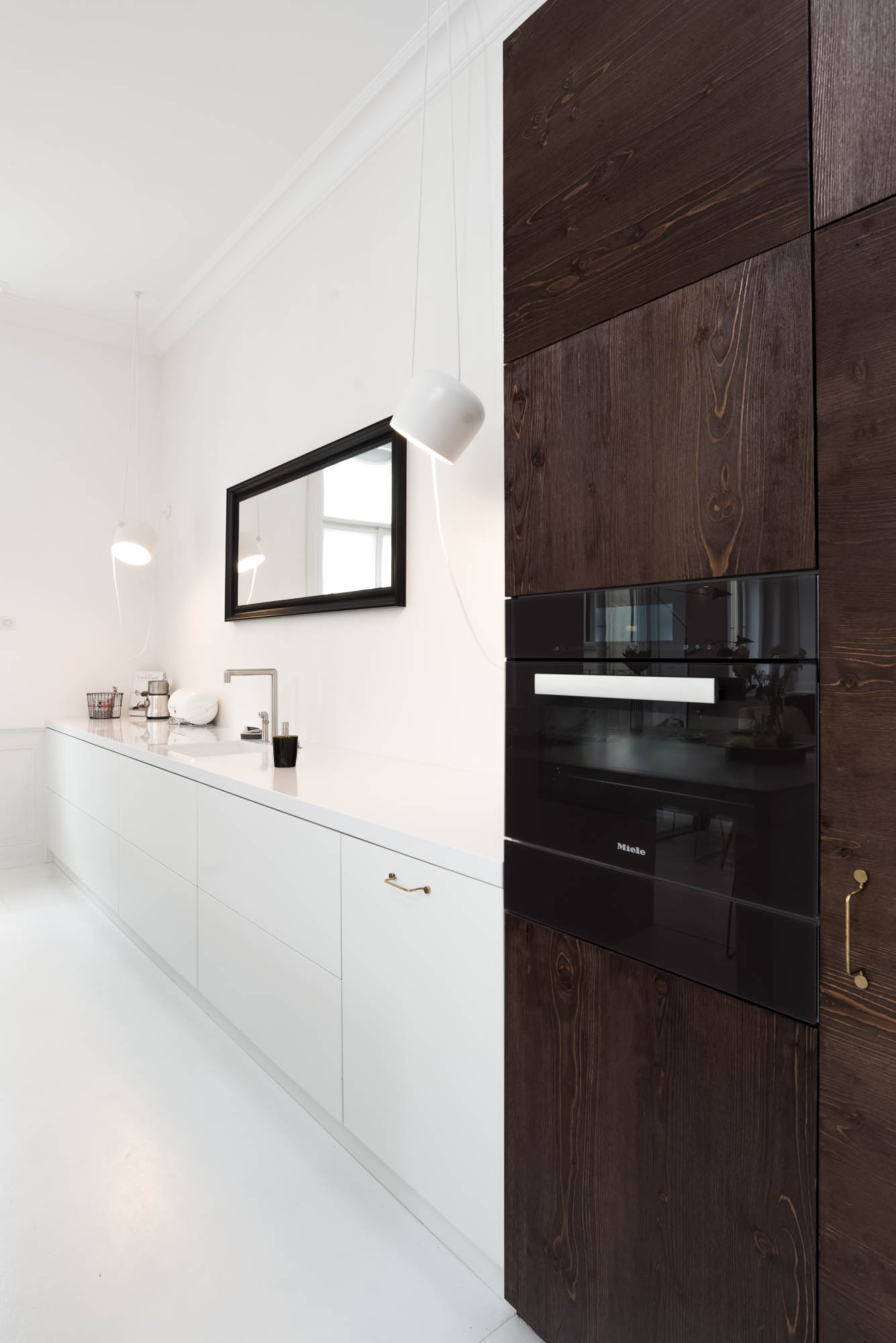 Kitchen cabinetry without upper cabinets, mirror above the work area and tall appliance cabinet – reconstruction design by OOOOX