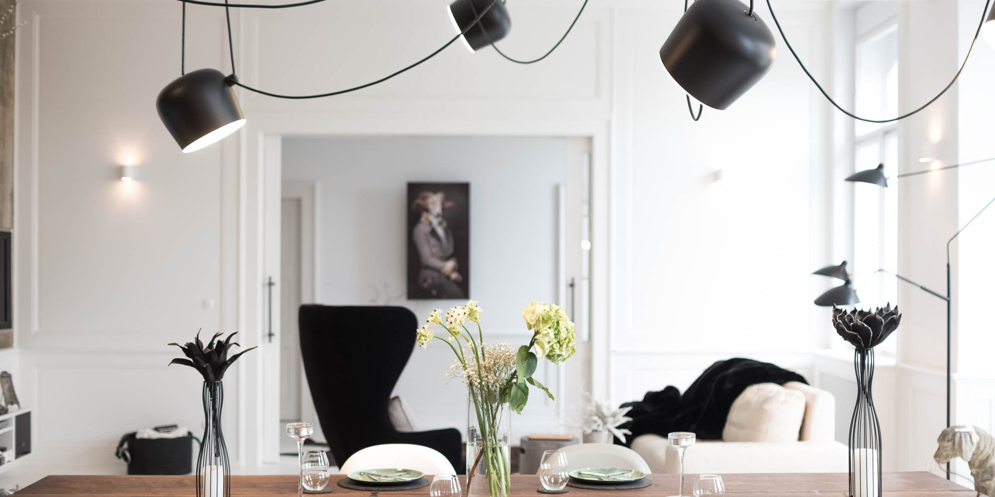 View of the living room across a solid walnut dining table – reconstruction and interior of an Art Nouveau apartment by OOOOX