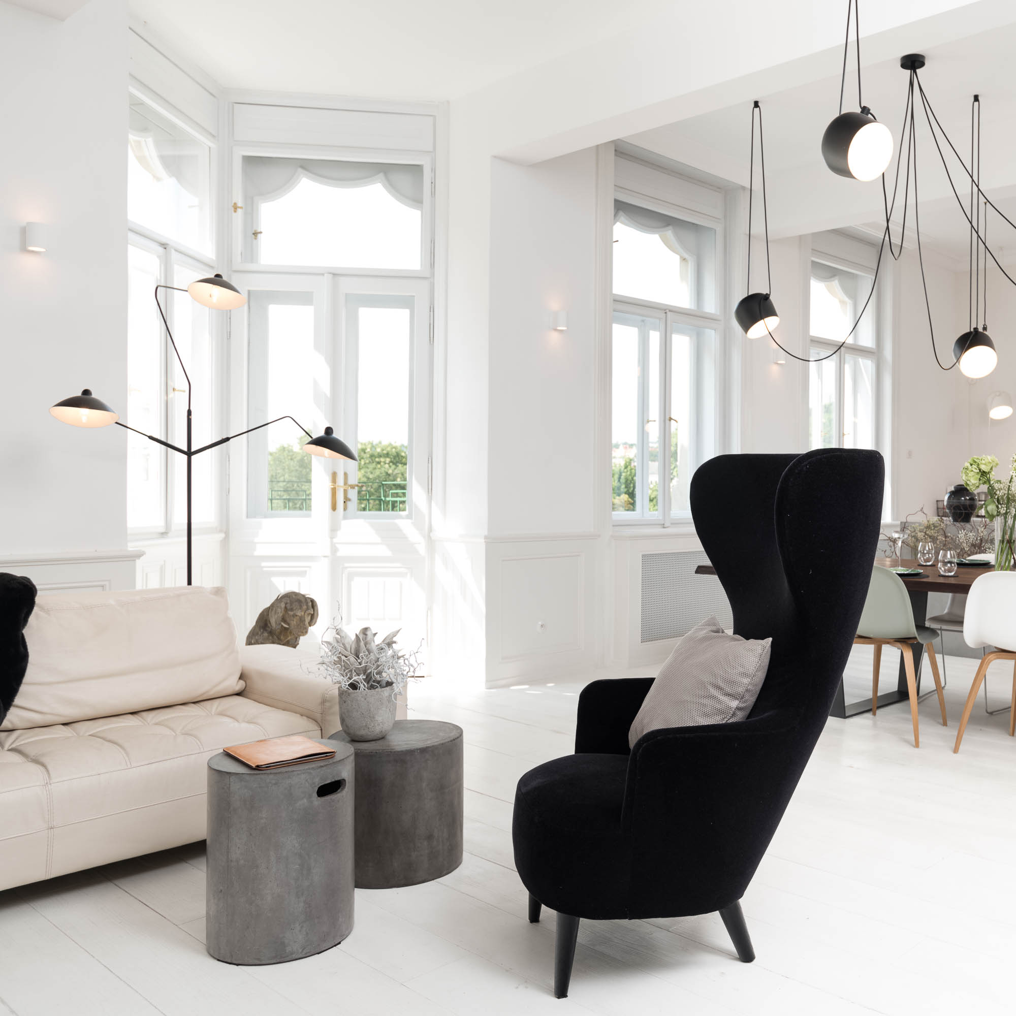 Living area of an Art Nouveau apartment with a designer black upholstered armchair, open space connected to the dining area and kitchen | interior design and reconstruction by OOOOX