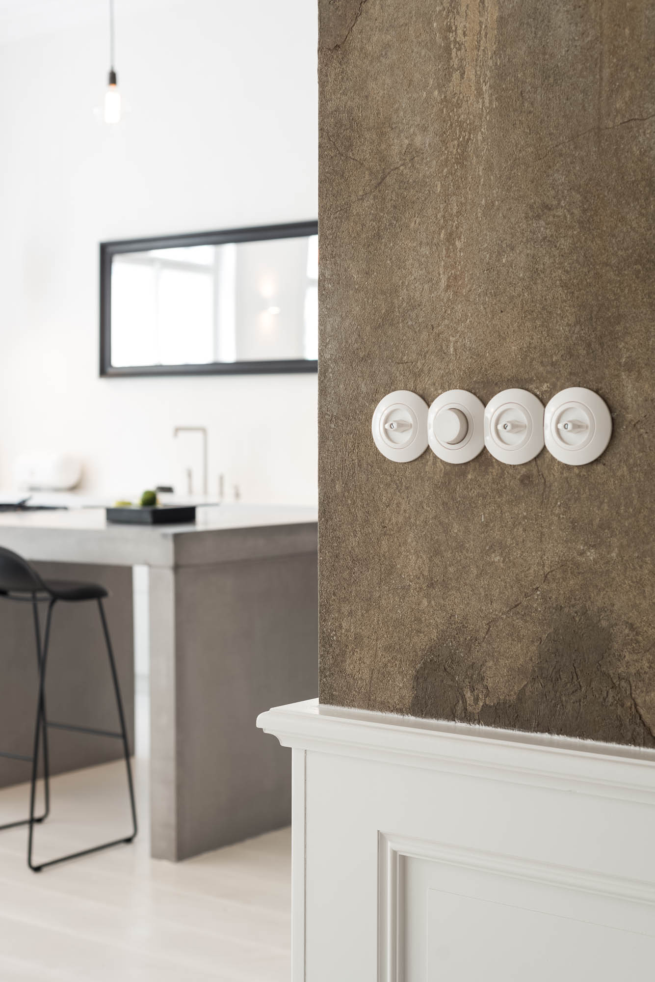 View of textured wall painting and a concrete kitchen island in the interior of the TIVOLI Art Nouveau apartment by OOOOX