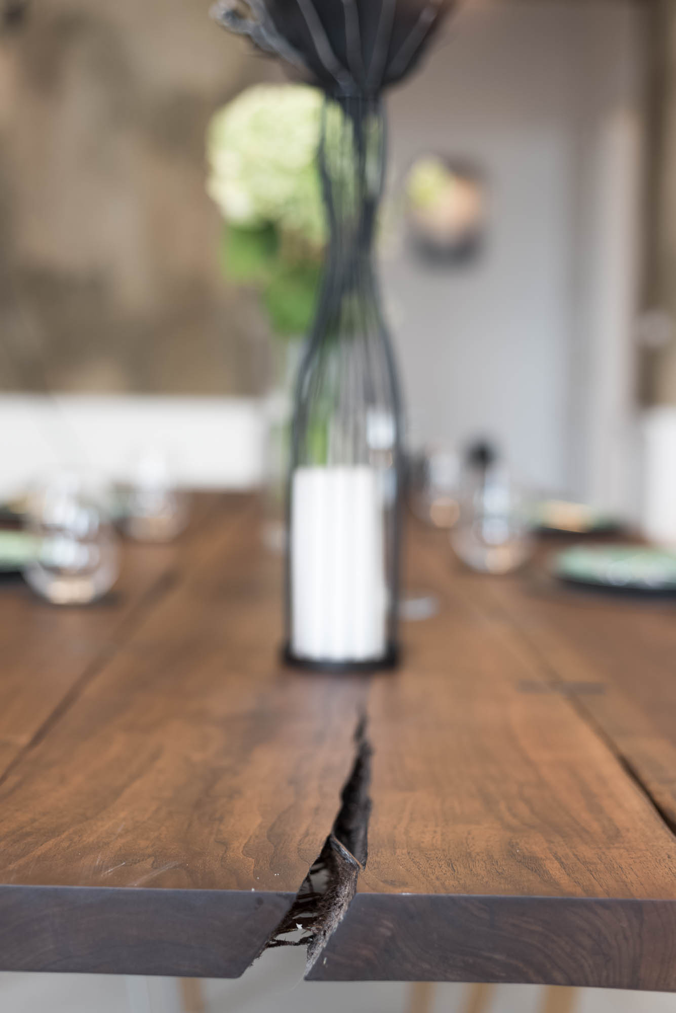 Detail of a three-metre solid walnut dining table with natural cracks joined by steel butterfly joints | Art Nouveau apartment reconstruction design by OOOOX