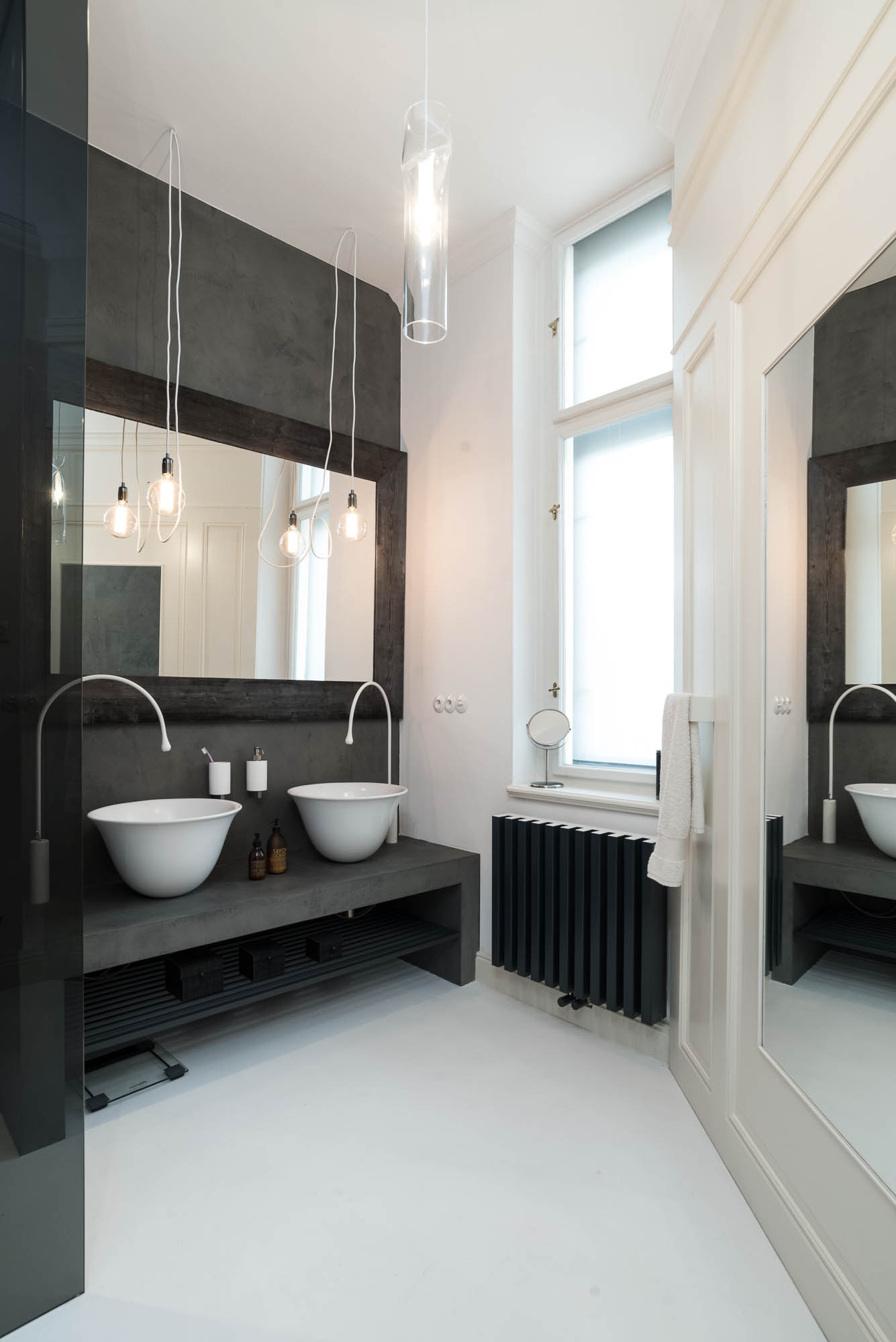 Concrete finish, two white sinks and a darker-toned bathroom in the TIVOLI Art Nouveau apartment | design by OOOOX