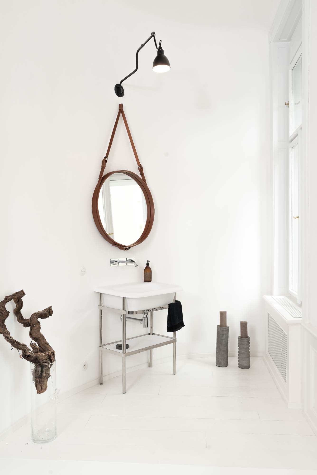 Detail of a sink and delicate vanity cabinet with a designer circular mirror, white interior of the TIVOLI Art Nouveau apartment | design by OOOOX