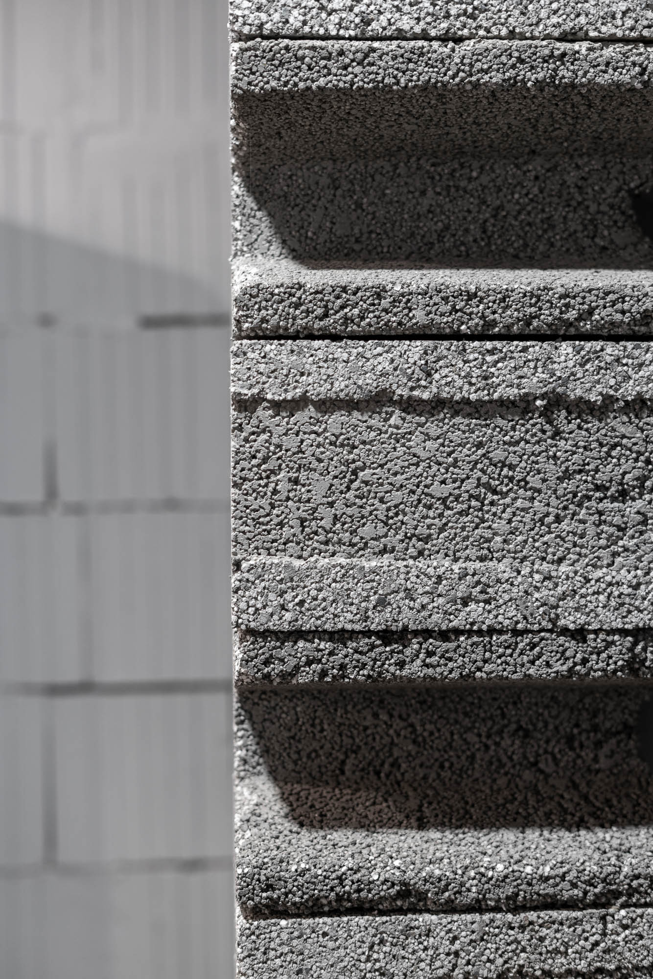 Makro záběr na strukturu přiznané betonové tvárnice v ostrém přirozeném světle v Pražírně Oltyně – povrch a textura hrubého stavebního materiálu