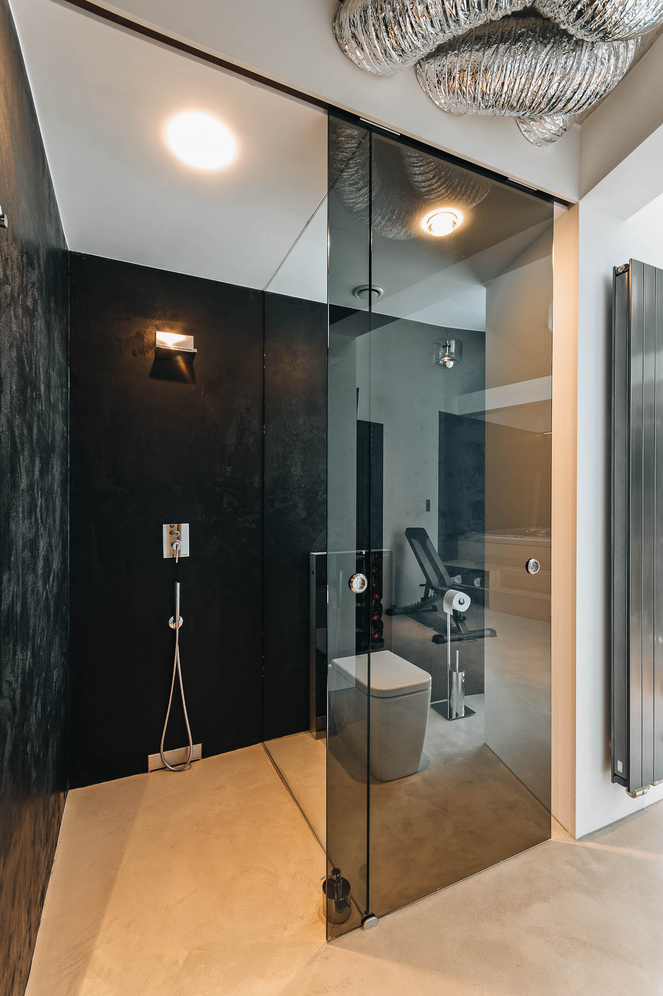 Sprchový kout a záchod oddělené kouřovým sklem ve wellness části vily s pohledovým betonem, OOOOX