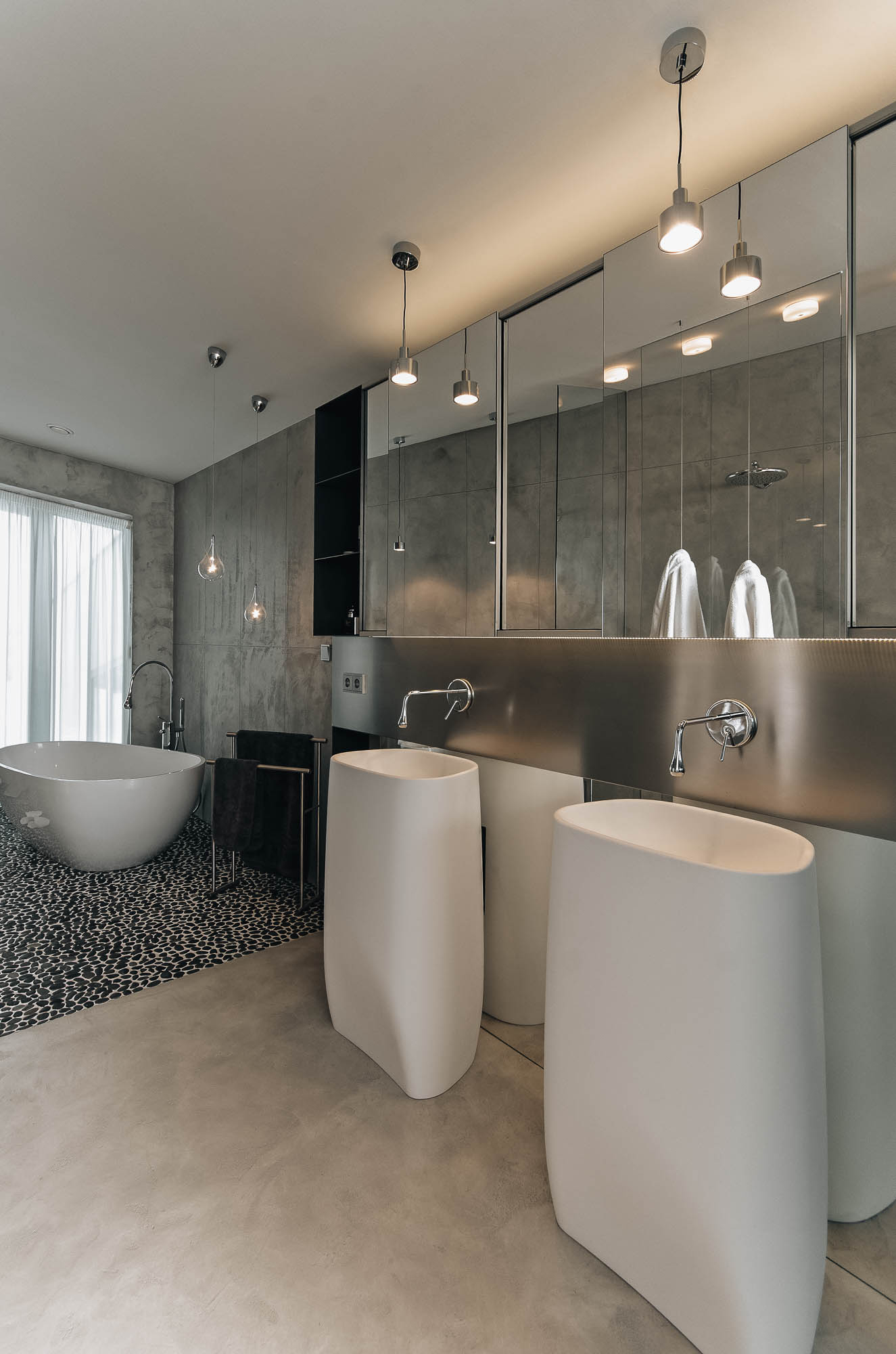 Dvě volně stojící umyvadla v koupelně vily s nerezovou zadní deskou, zrcadlovým kabinetem a vanou