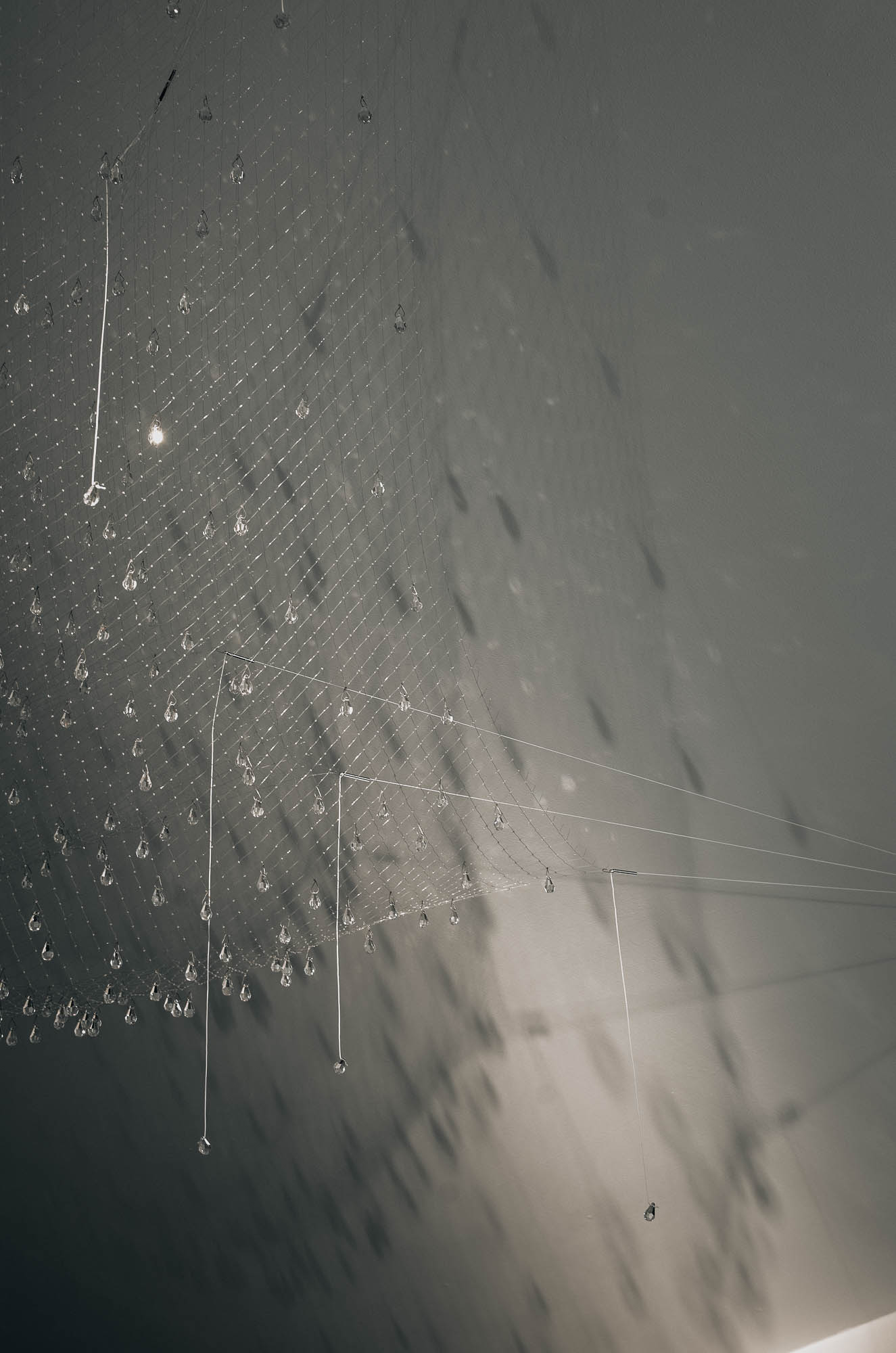 Detail křišťálové sítě svítidla nad pohledovým betonovým stropem v ložnici interiéru vily, OOOOX