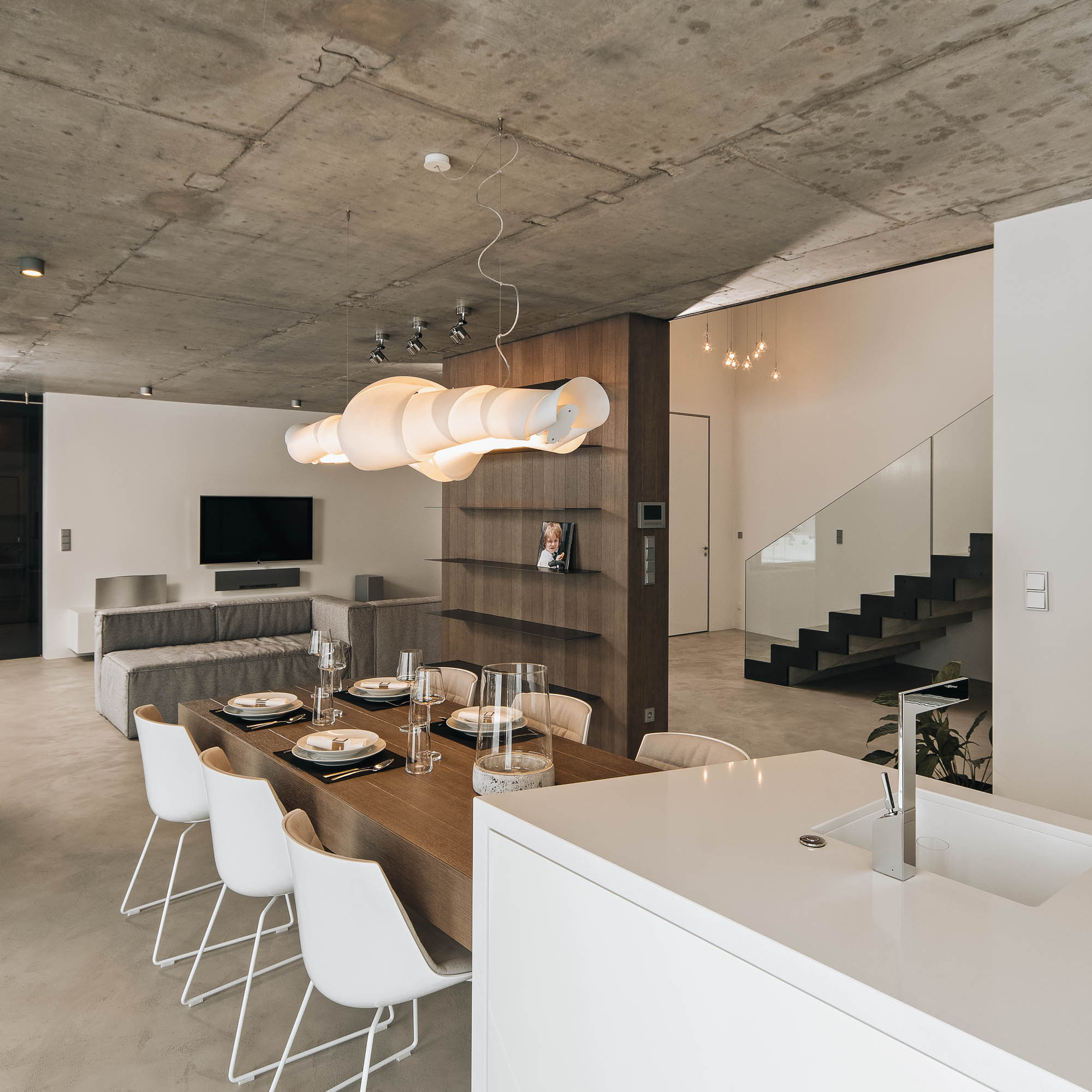 Otevřený prostor vily z pohledu kuchyňského ostrůvku – jídelna, obývací pokoj a schodiště, kuchyně s vykonzolovaným jídelním stolem, OOOOX