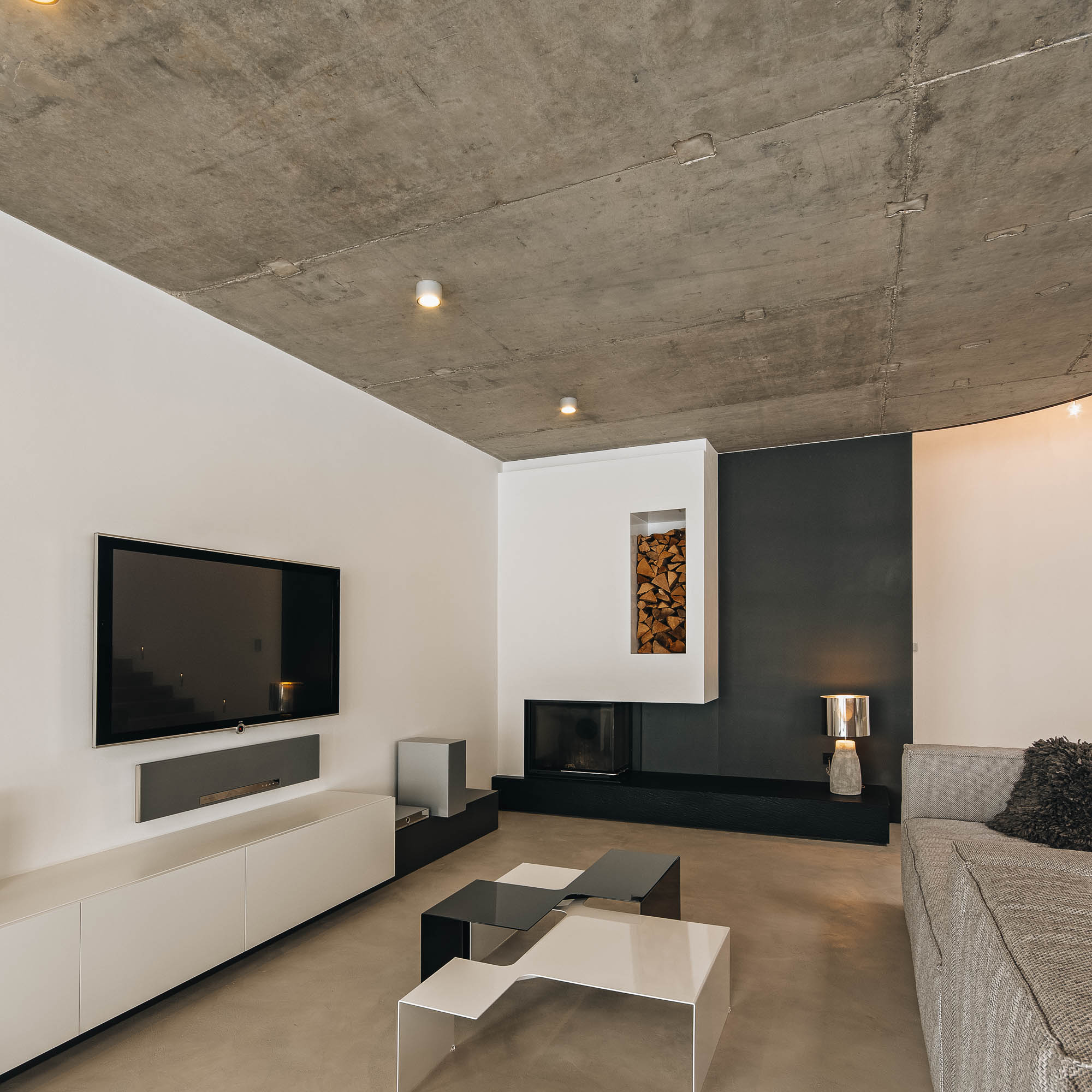 Panorama otevřeného prostoru vily – obývací pokoj s krbem, jídelna a kuchyně, pohledový beton, OOOOX