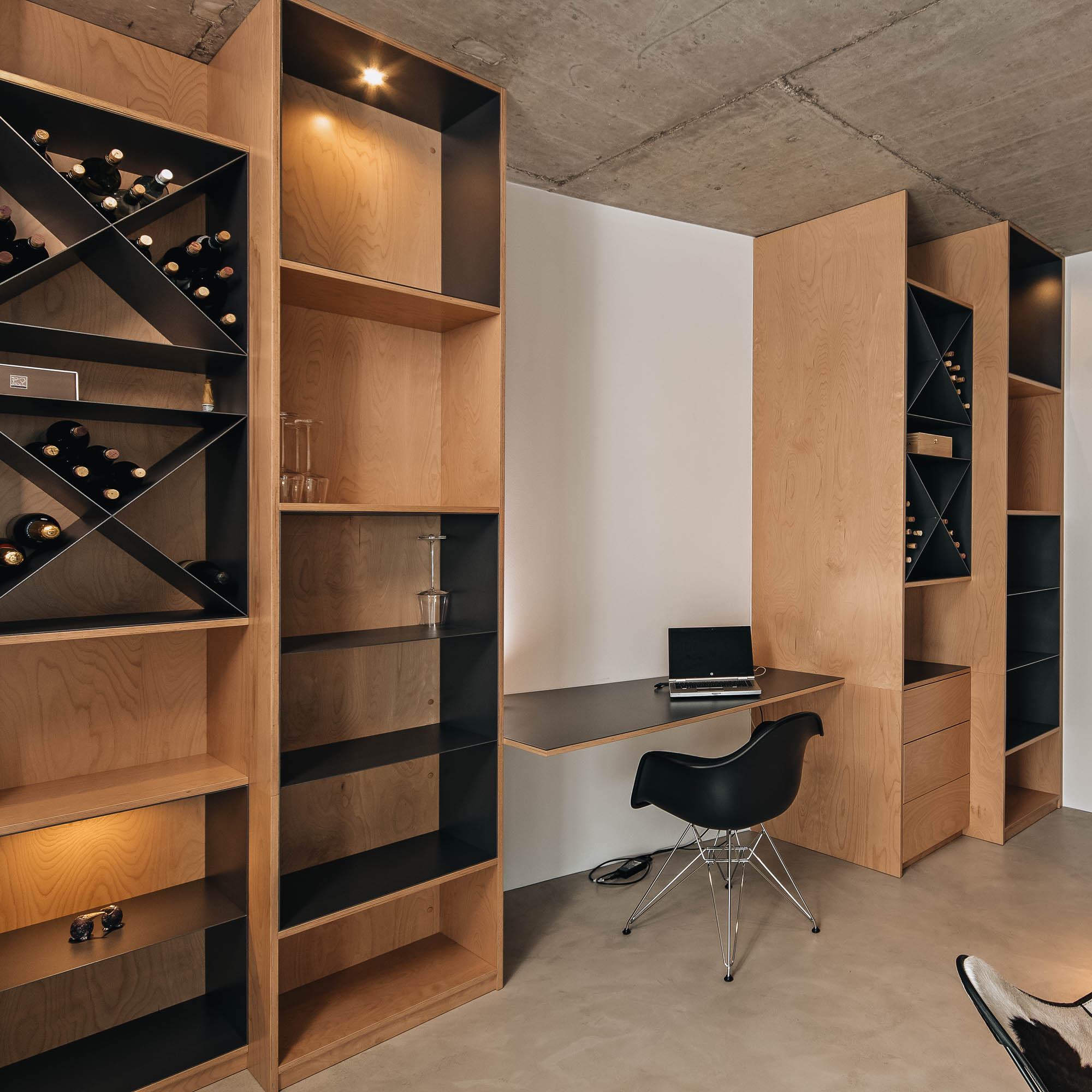 Překližkový policový systém s úložištěm na víno v kuřárně interiéru vily s pohledovým betonem, OOOOX