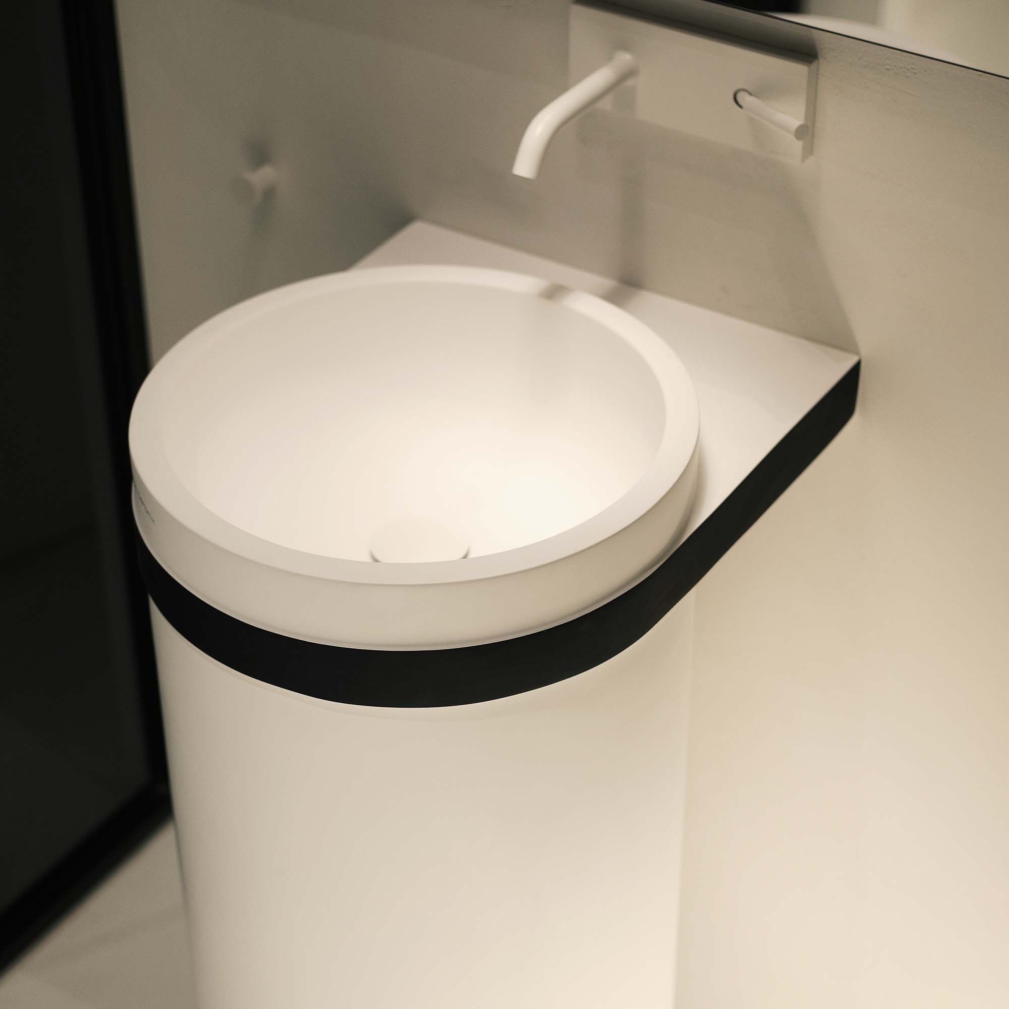 Detail designového bílého kulatého umyvadla na podstavci s černým okrajem – koupelna rekonstrukce bytu Pařížská, minimalistické pojetí s nástěnnou bílou baterií