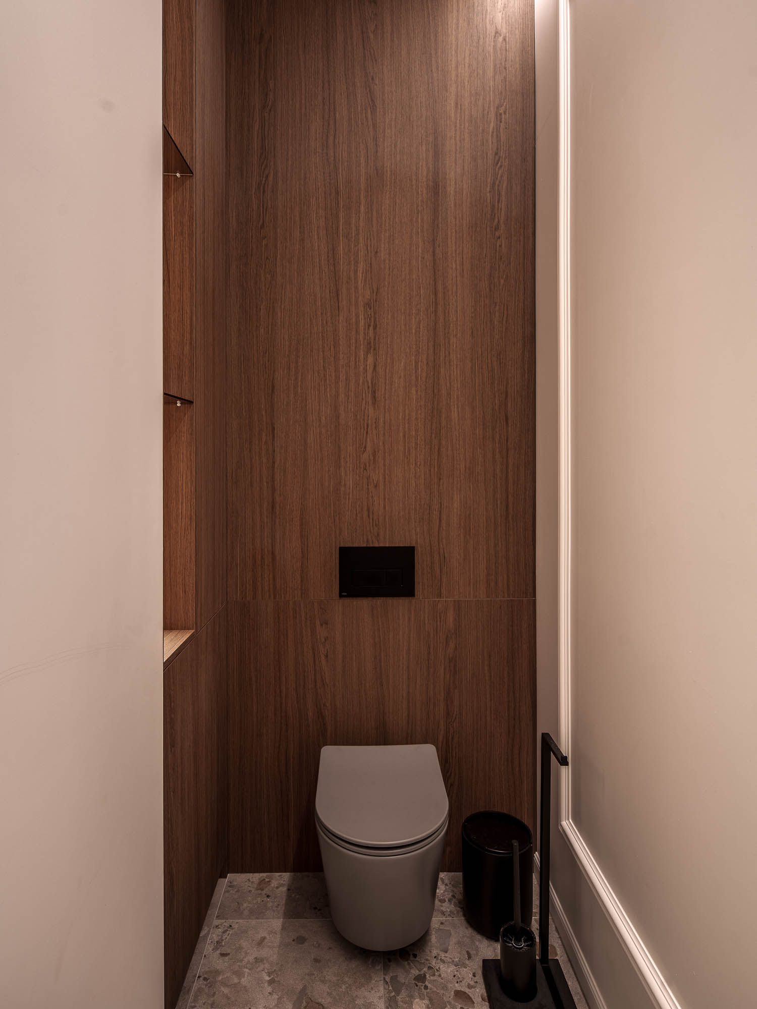 WC zázemí butiku LA TABLE Pařížská – závěsné WC s tmavým dřevěným obkladem, černým splachováním a lineárním LED osvětlením – OOOOX