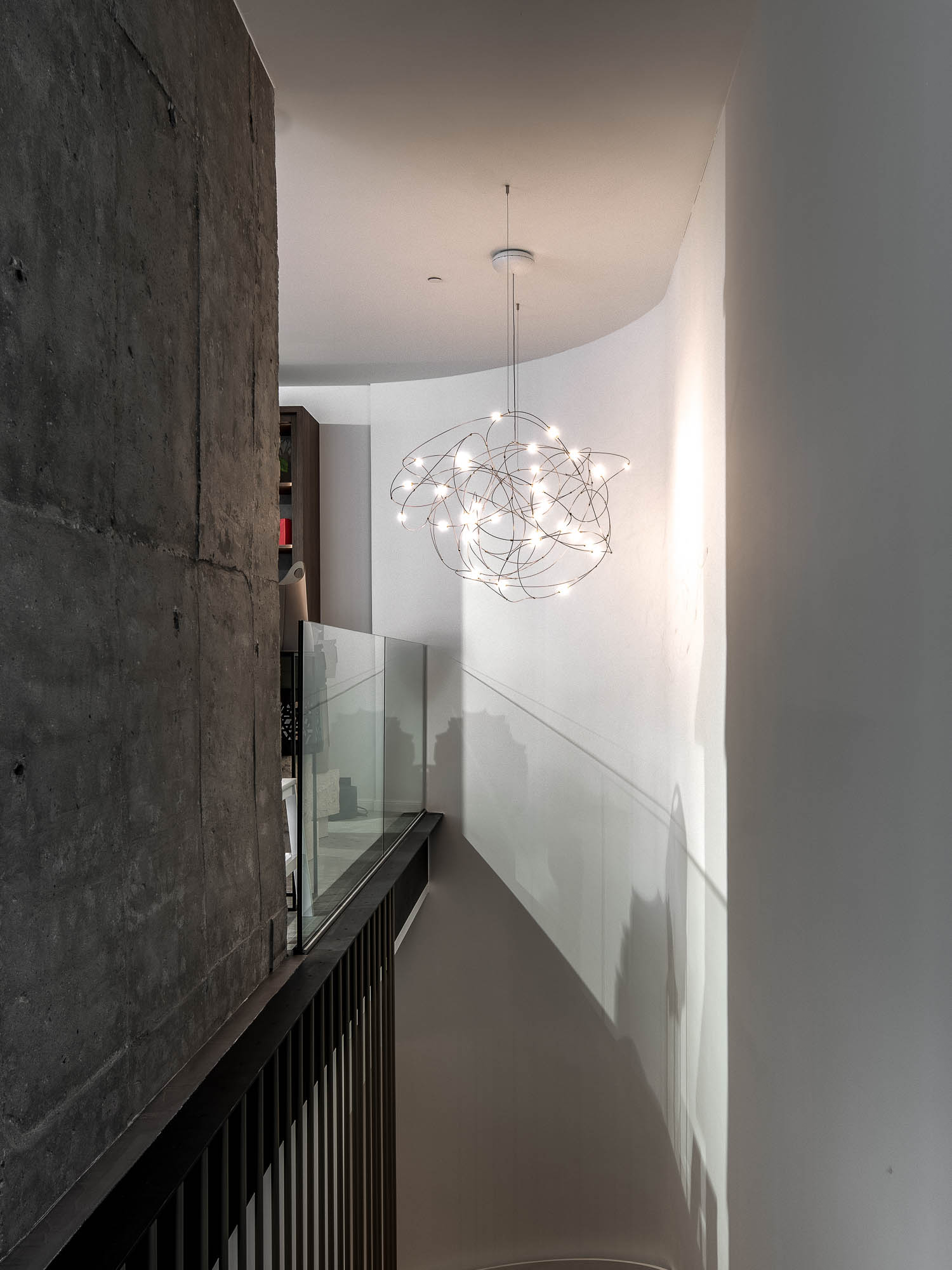 Závěsné svítidlo Moooi Flock of Light v schodišťovém prostoru showroomu LA TABLE Pařížská – bílá zakřivená stěna a přiznaný betonový pilíř – OOOOX