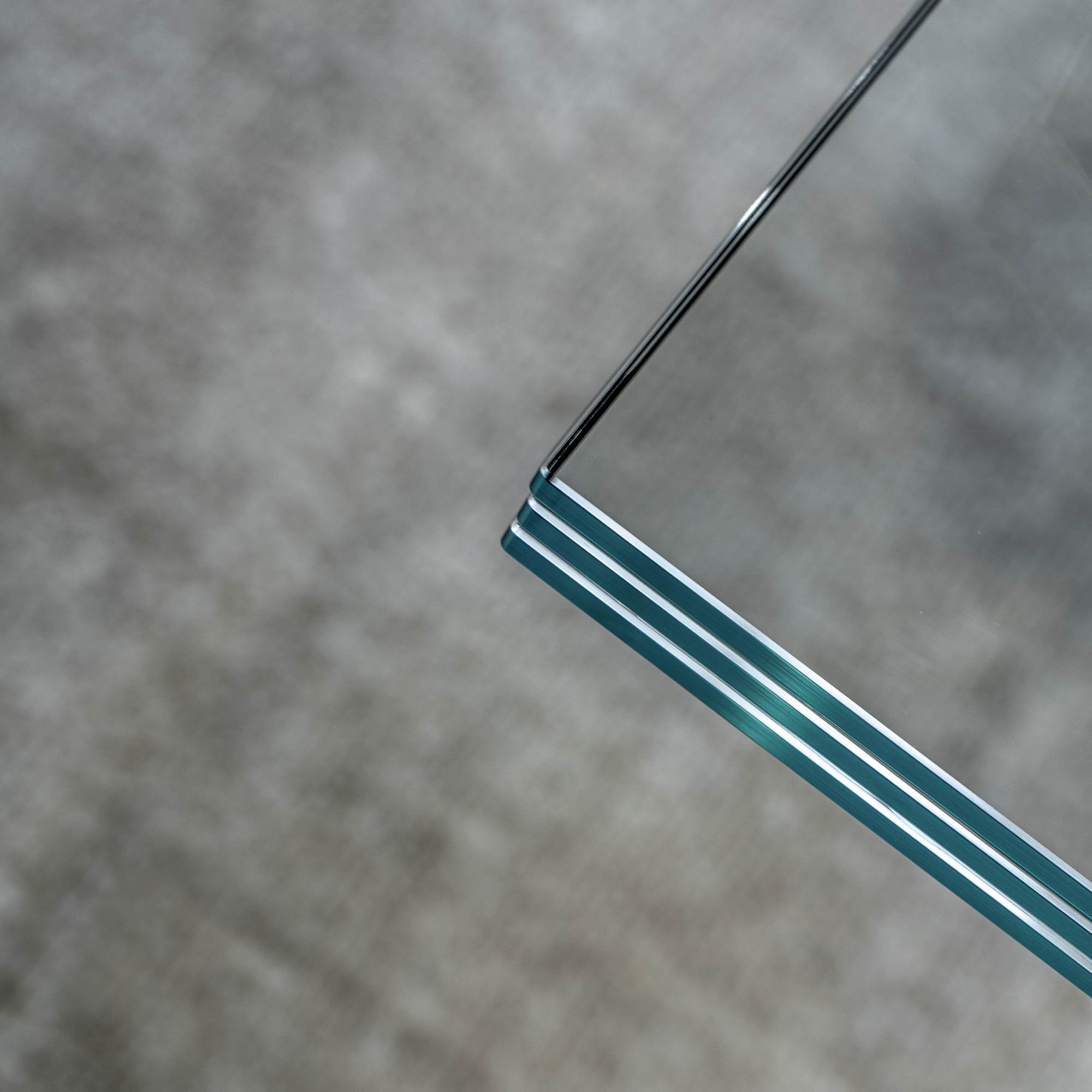 Detail hrany desky centrálního stolu showroomu LA TABLE Pařížská – tři vrstvy bezpečnostního skla s tyrkysovým nádechem viditelné v průřezu – OOOOX design
