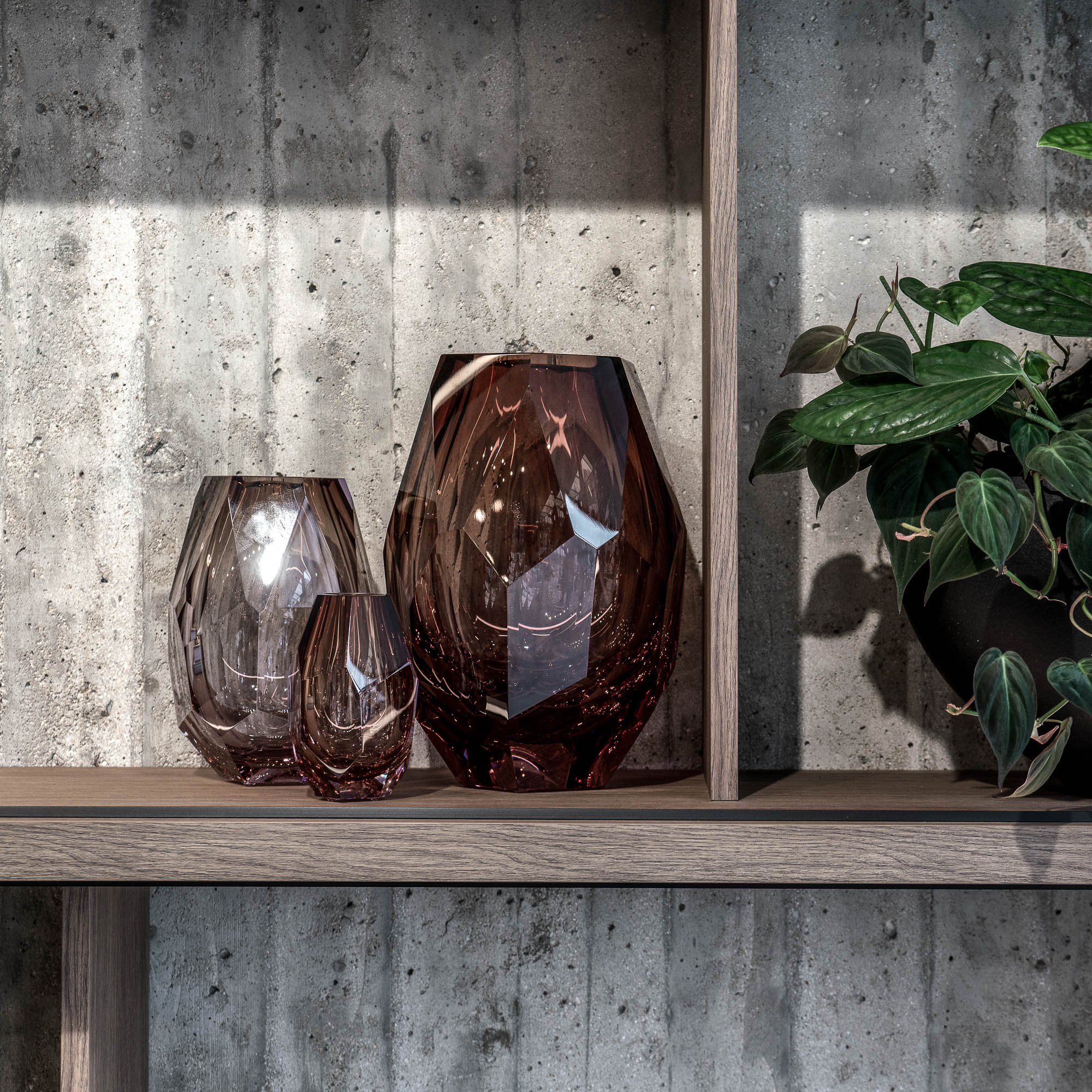 Detail dvou fazetovaných skleněných váz v kouřovém hnědém odstínu na dubové polici před přiznanou betonovou stěnou – showroom LA TABLE Pařížská OOOOX