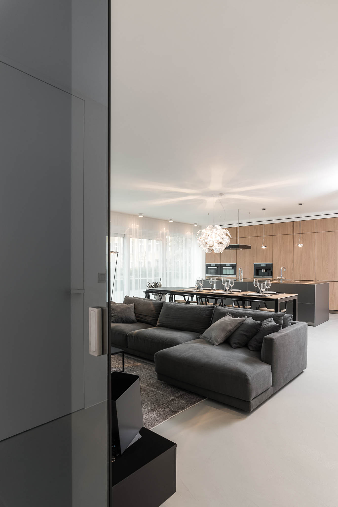 Tmavá sedačka v obývacím pokoji s designovým křeslem – minimalistický interiér | OOOOX